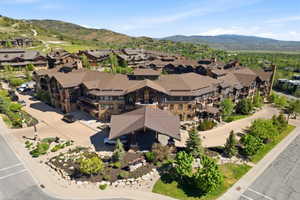 Expansive multi-story building featuring stone and wood siding, multiple balconies, a covered entryway, and mature landscaping