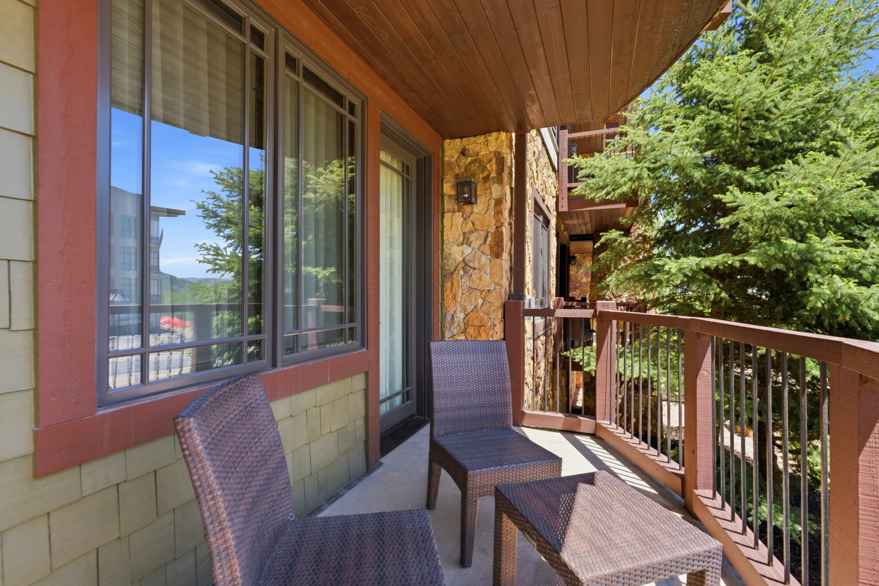 Private balcony with concrete flooring, wood-paneled ceiling, and a stone accent wall