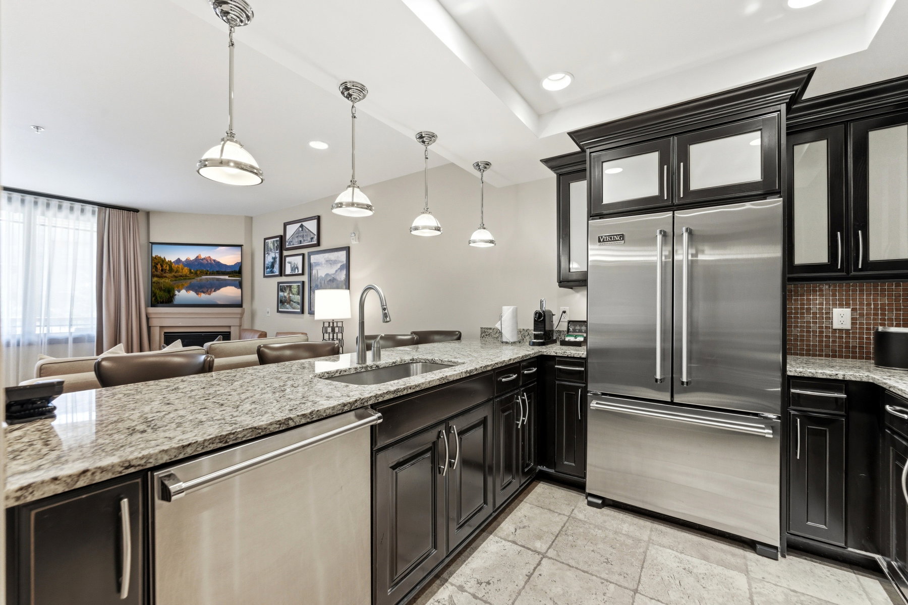 Kitchen featuring granite countertops, dark wood cabinetry, stainless steel appliances, and pendant lighting