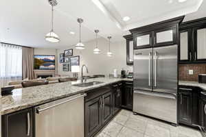 Kitchen featuring granite countertops, dark wood cabinetry, stainless steel appliances, and pendant lighting