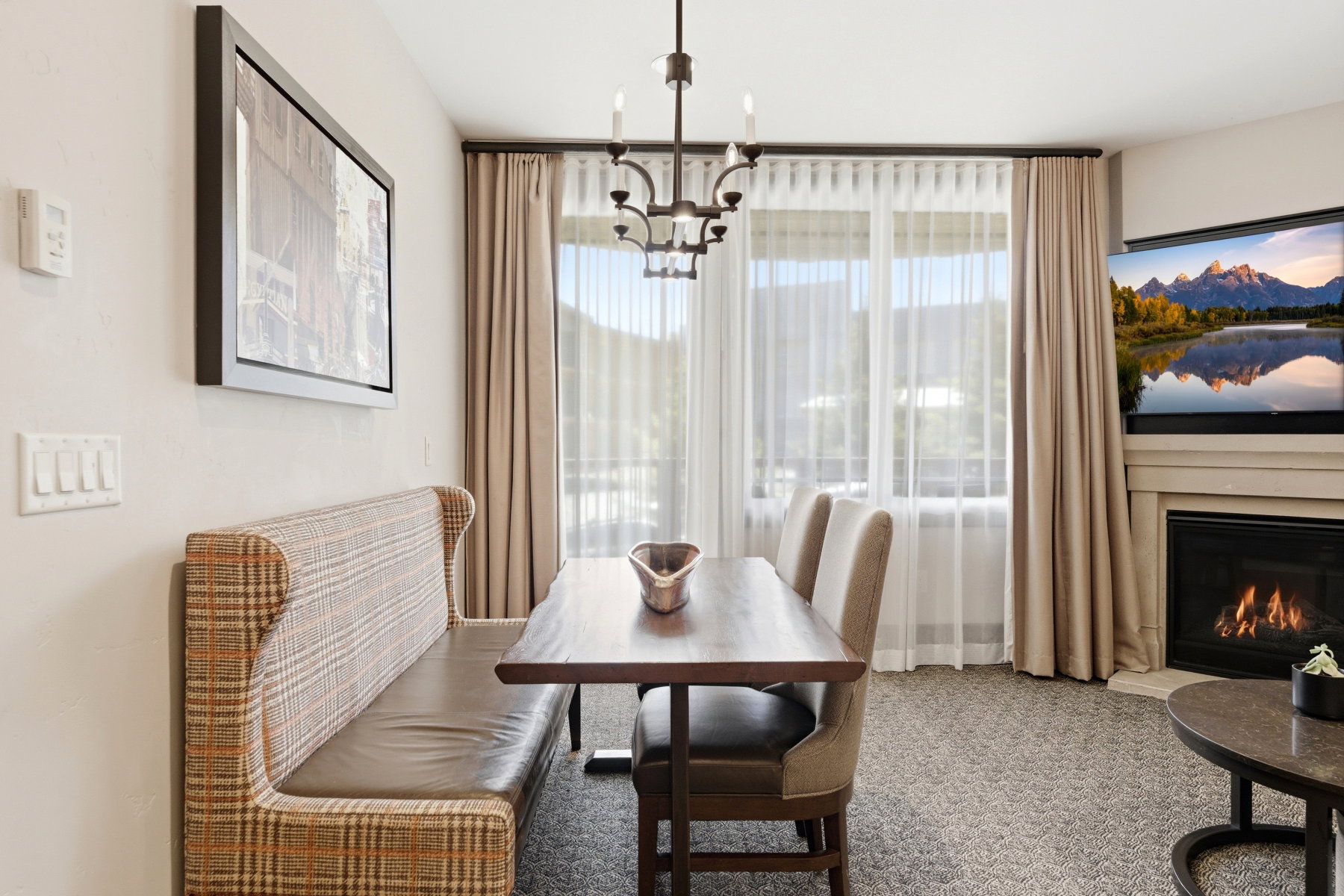 Dining area with a built-in banquette, central chandelier, and large window