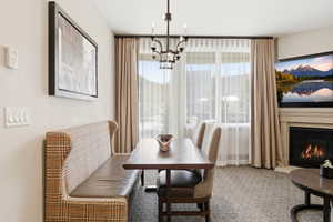 Dining area with a built-in banquette, central chandelier, and large window