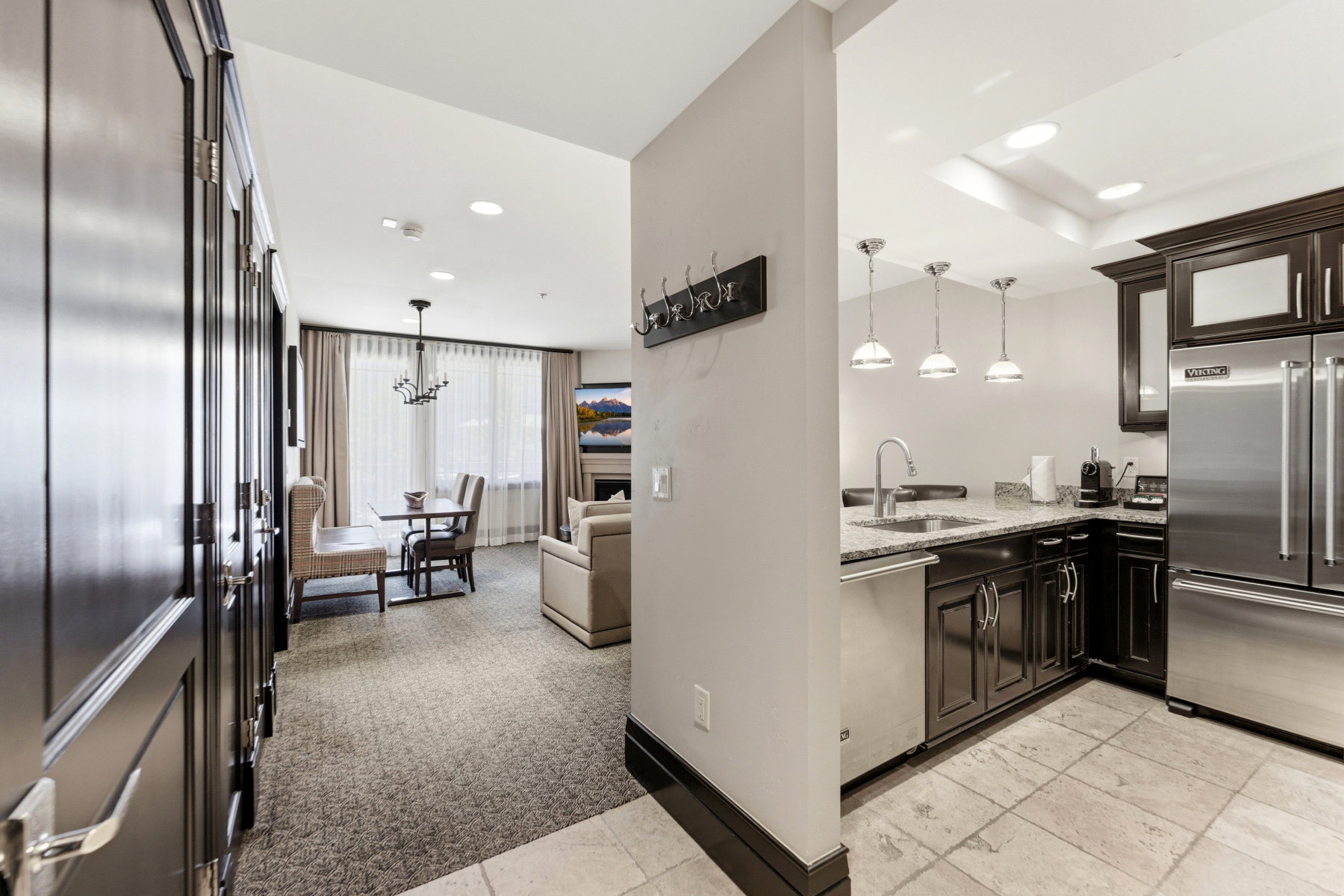 Open-concept living space featuring a full kitchen with stainless steel appliances, granite countertops, and dark wood cabinetry