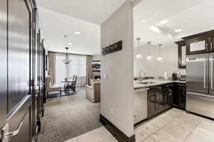 Open-concept living space featuring a full kitchen with stainless steel appliances, granite countertops, and dark wood cabinetry