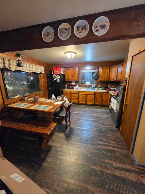 Kitchen featuring wood-finish flooring, warm-toned cabinetry, and a black appliance suite