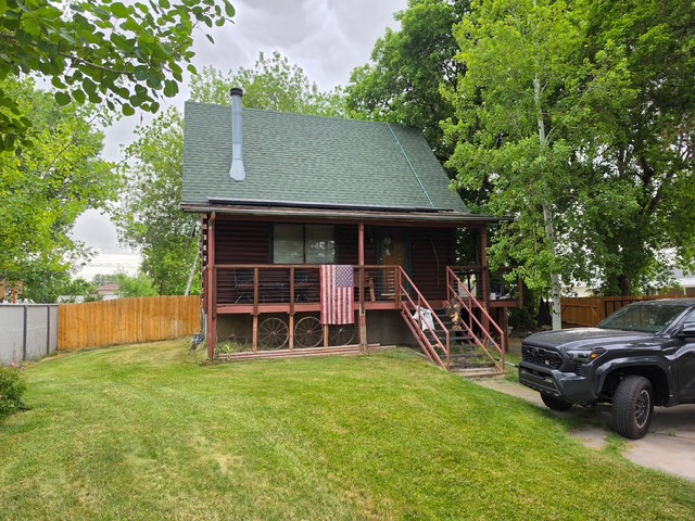 Log cabin exterior with a green asphalt shingle roof