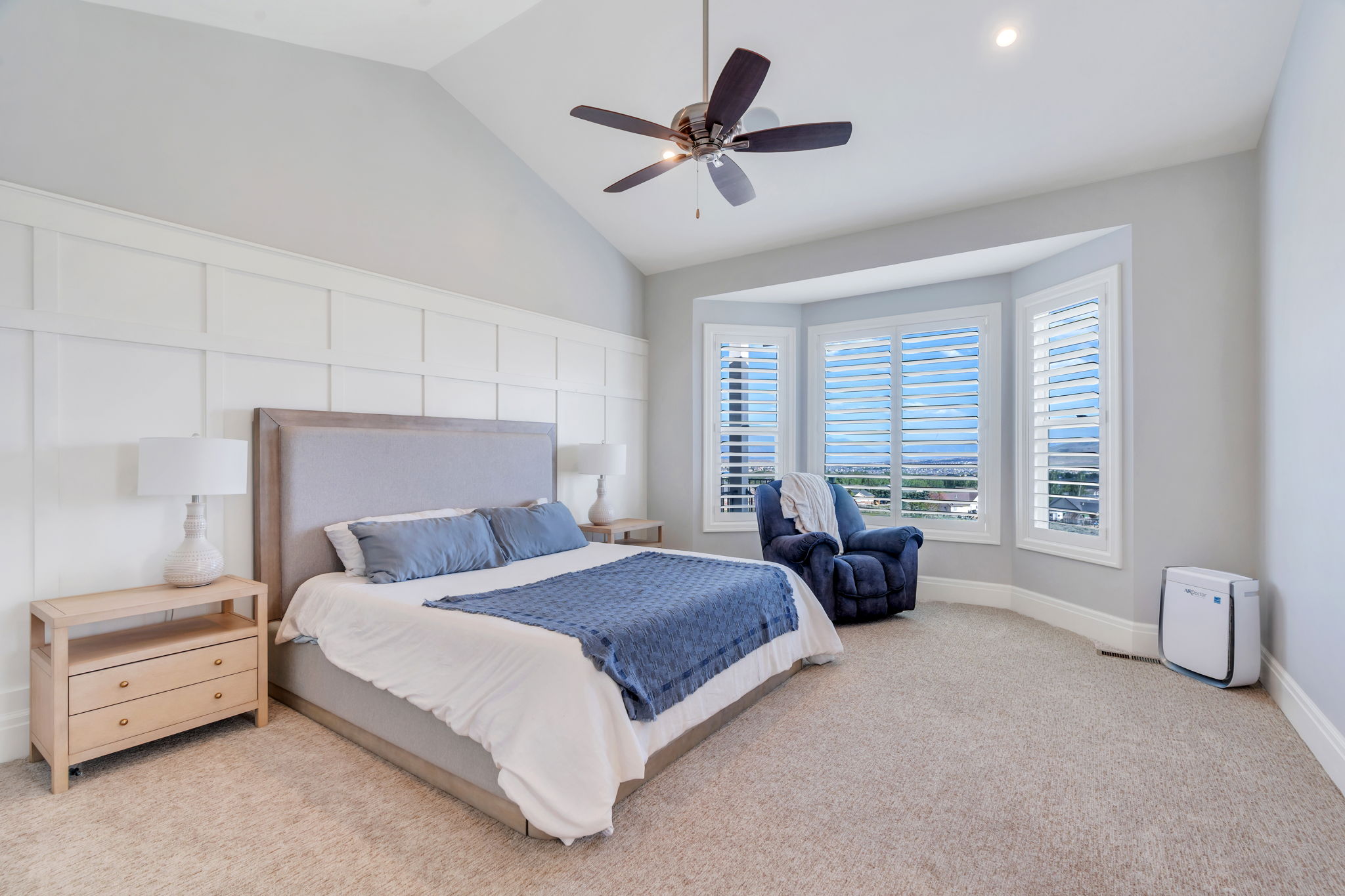 Bedroom featuring a vaulted ceiling with a ceiling fan, a board and batten accent wall, and plush carpeting