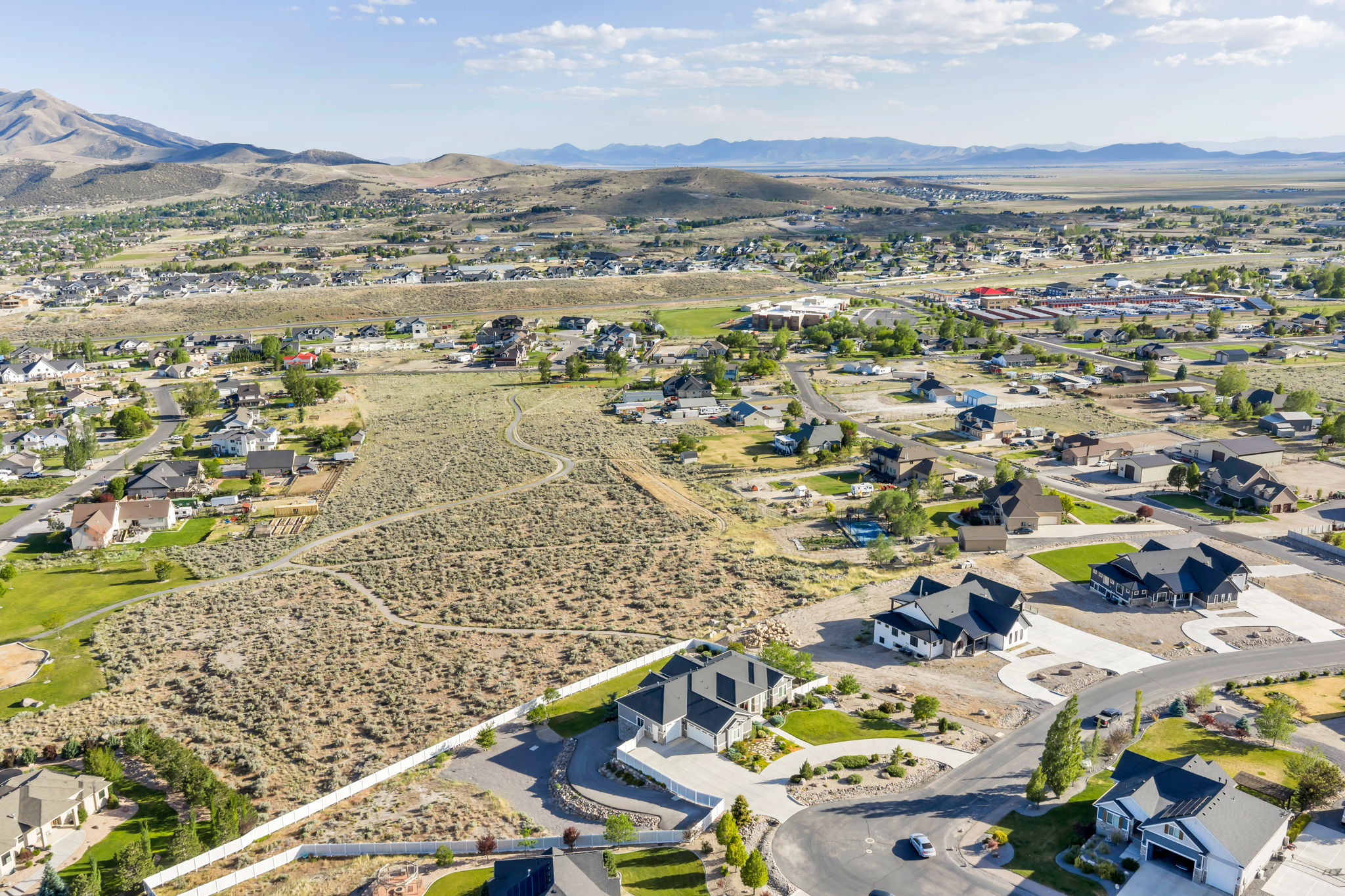 Expansive undeveloped land parcel featuring natural desert flora, bordering established residential properties