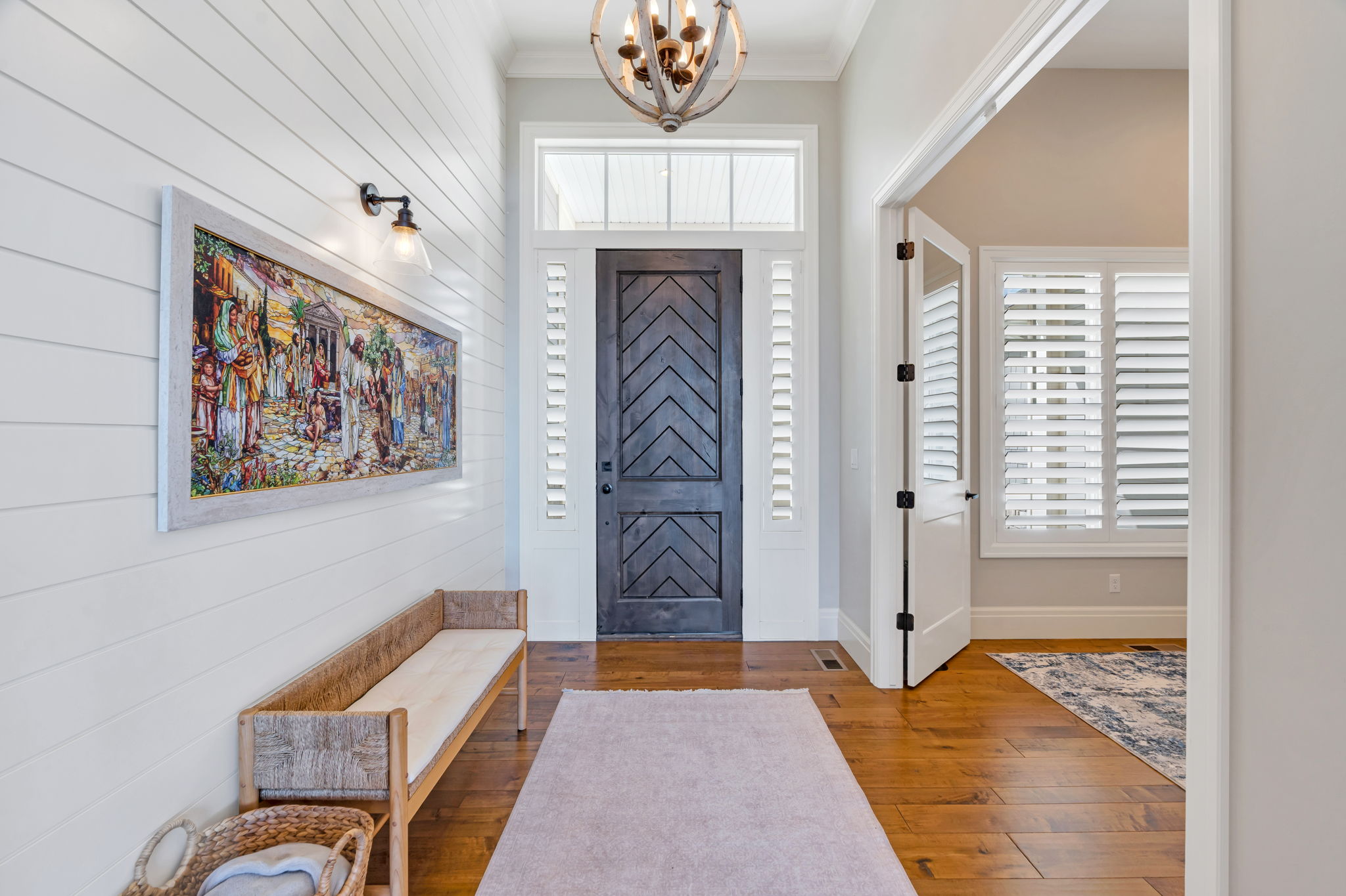 Foyer featuring wood-finish flooring, shiplap wall paneling, and a dark wood entry door with transom window