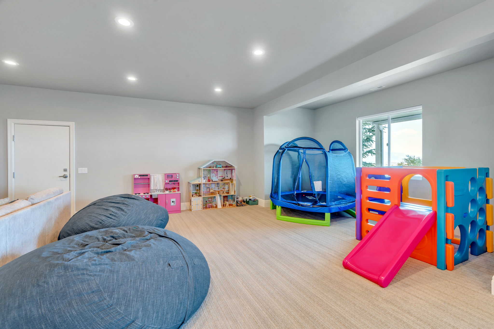 Spacious room featuring light-toned carpeting, recessed ceiling lighting, and a window providing natural illumination