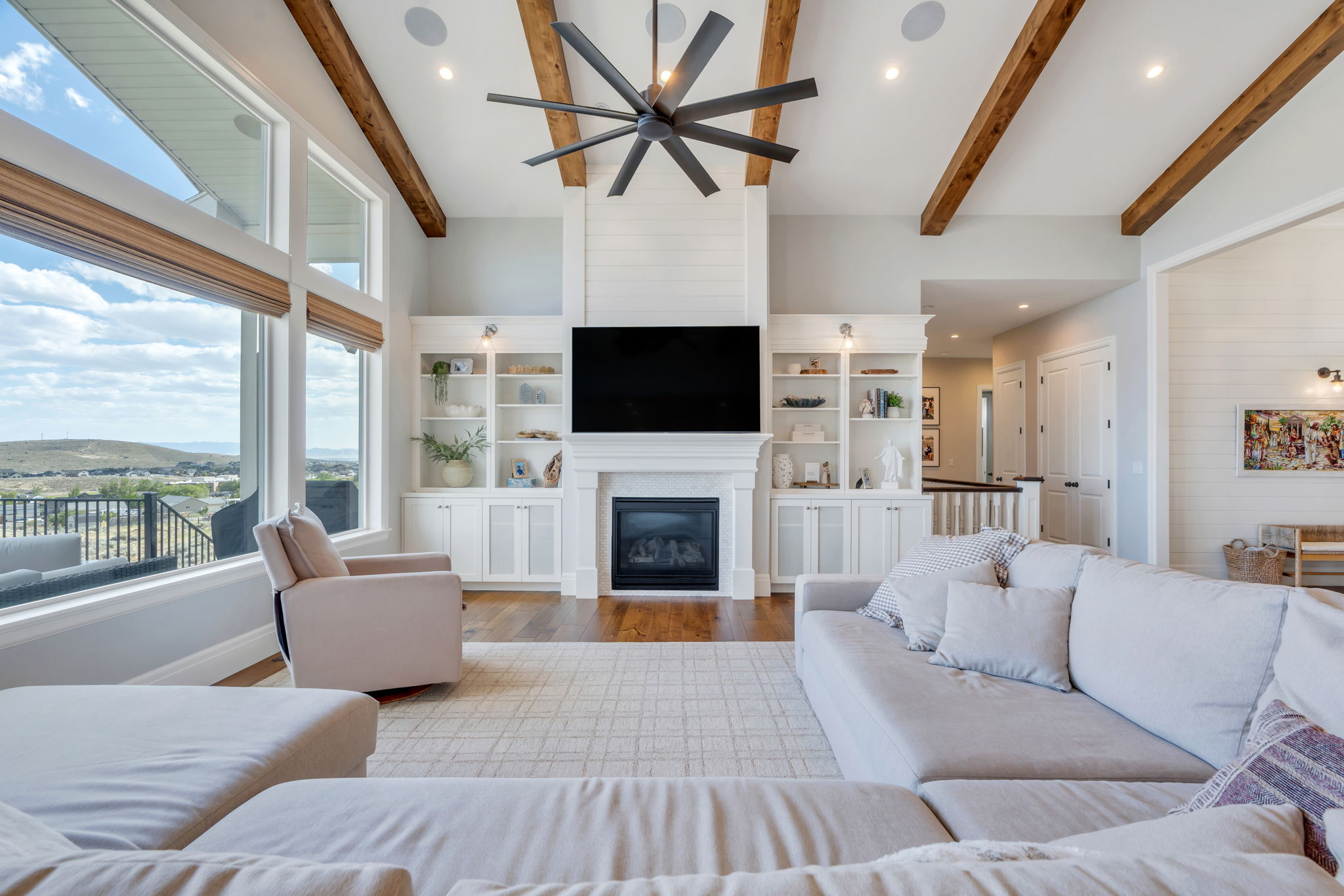 Spacious living area featuring exposed wood ceiling beams and a striking ceiling fan