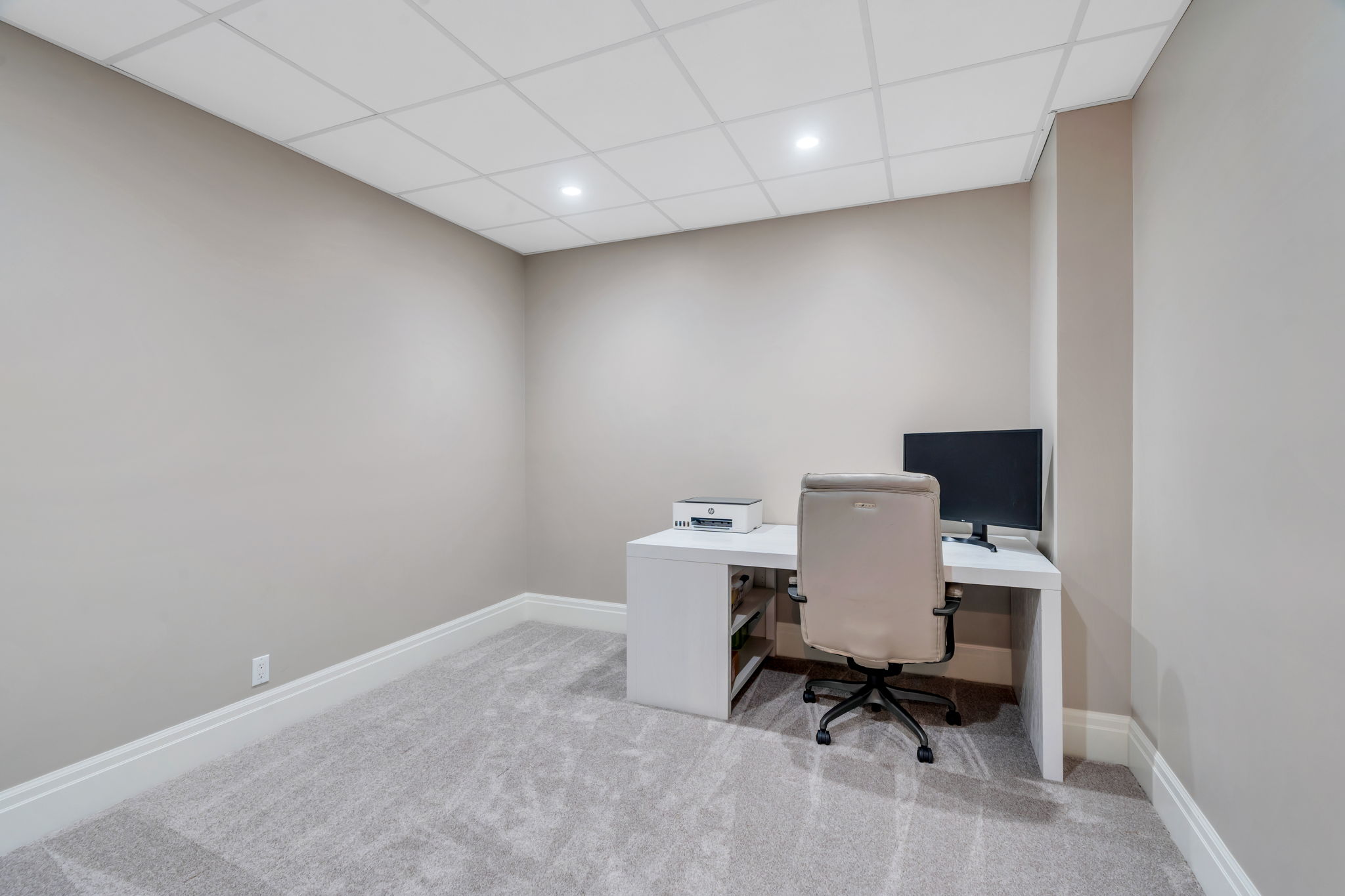Room featuring textured carpet flooring, neutral wall tones, white baseboards, and a grid panel ceiling with recessed lighting