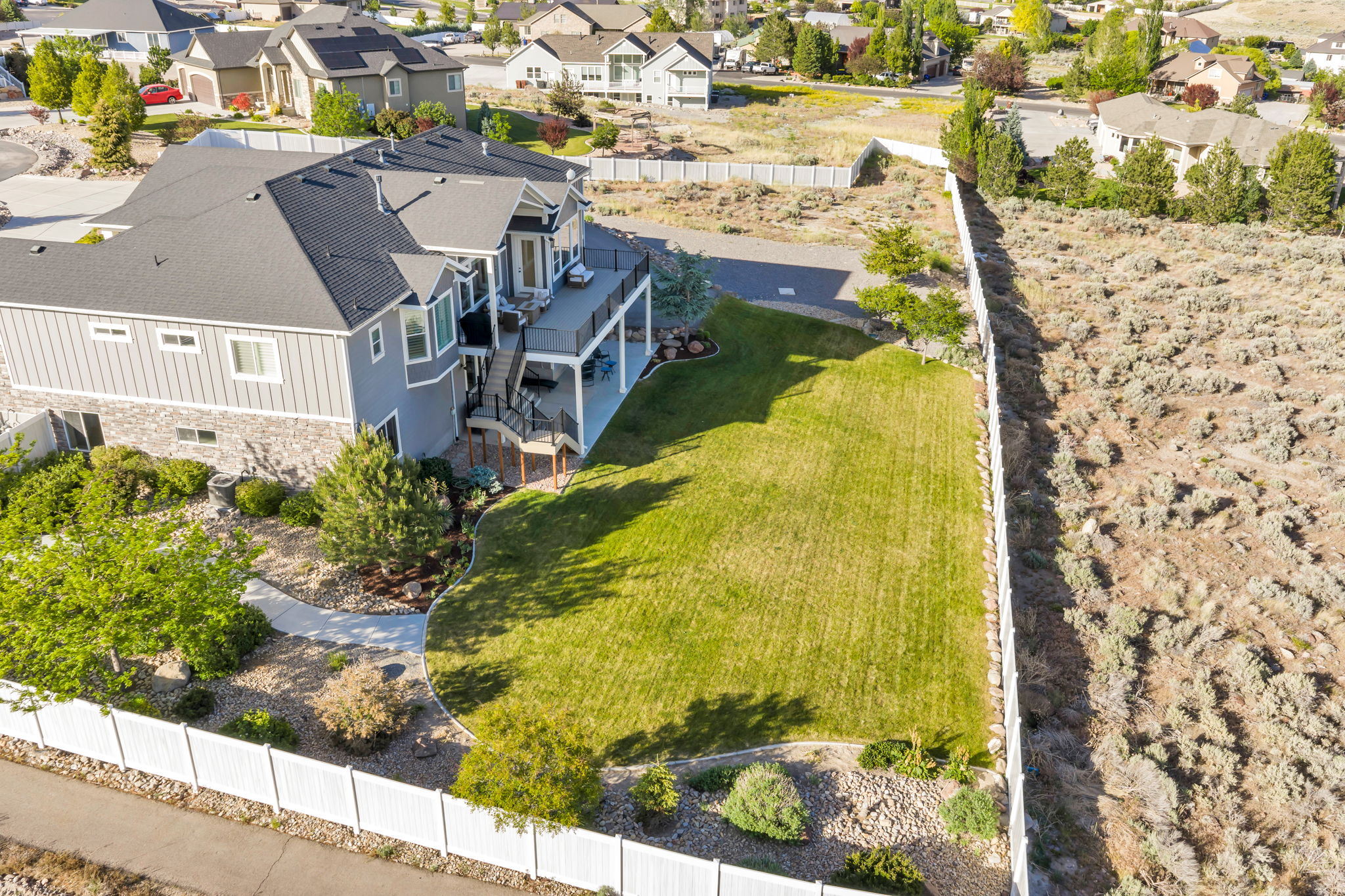 Rear exterior featuring a multi-level deck, a lower patio, and a spacious green lawn