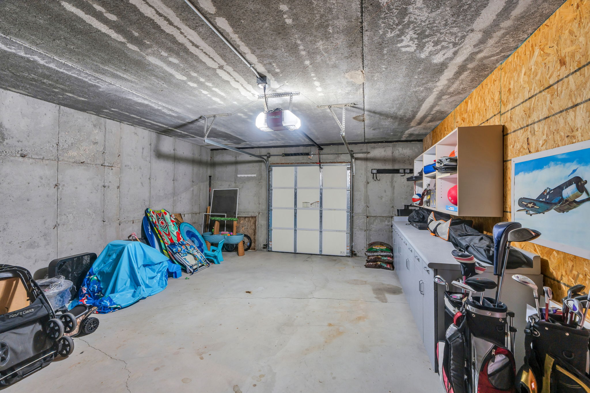 Attached garage with a concrete floor, built-in storage cabinetry, and exposed concrete walls