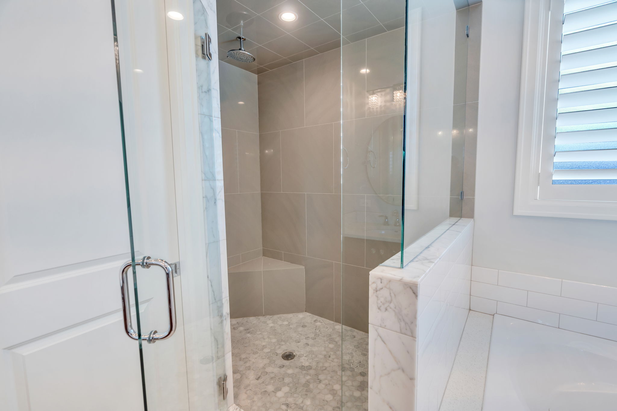 Glass-enclosed shower featuring a rain showerhead, built-in bench, and mosaic tile flooring