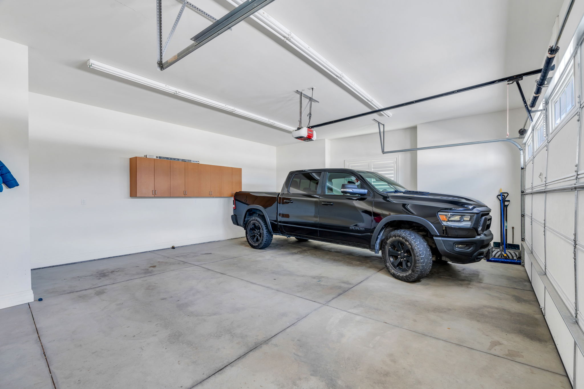 Attached garage featuring a concrete floor, built-in wall cabinetry, fluorescent lighting, and an automatic garage door opener