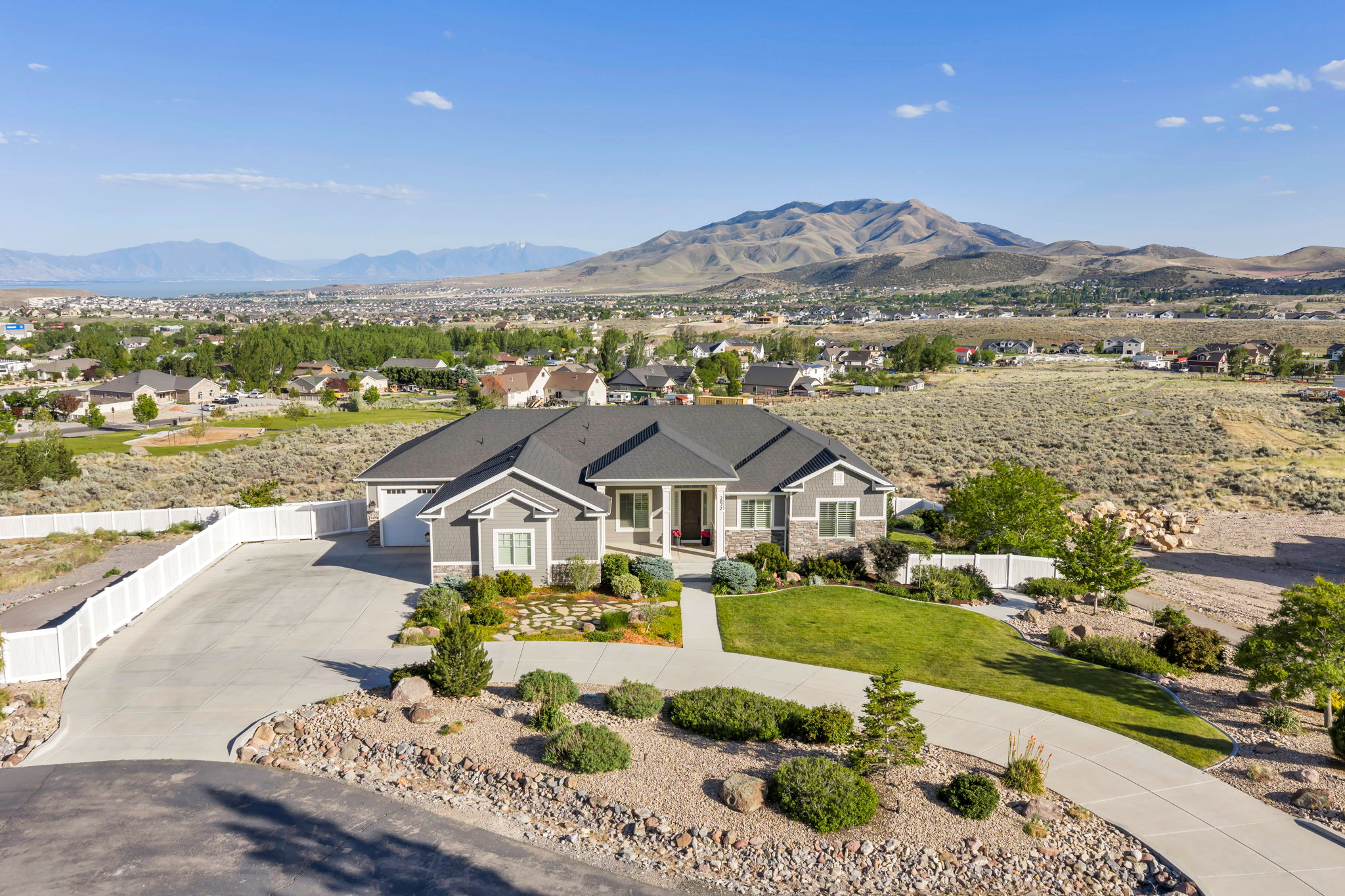 Contemporary ranch-style home featuring a two-car garage, stone and siding exterior, concrete driveway, and established landscaping with rock accents