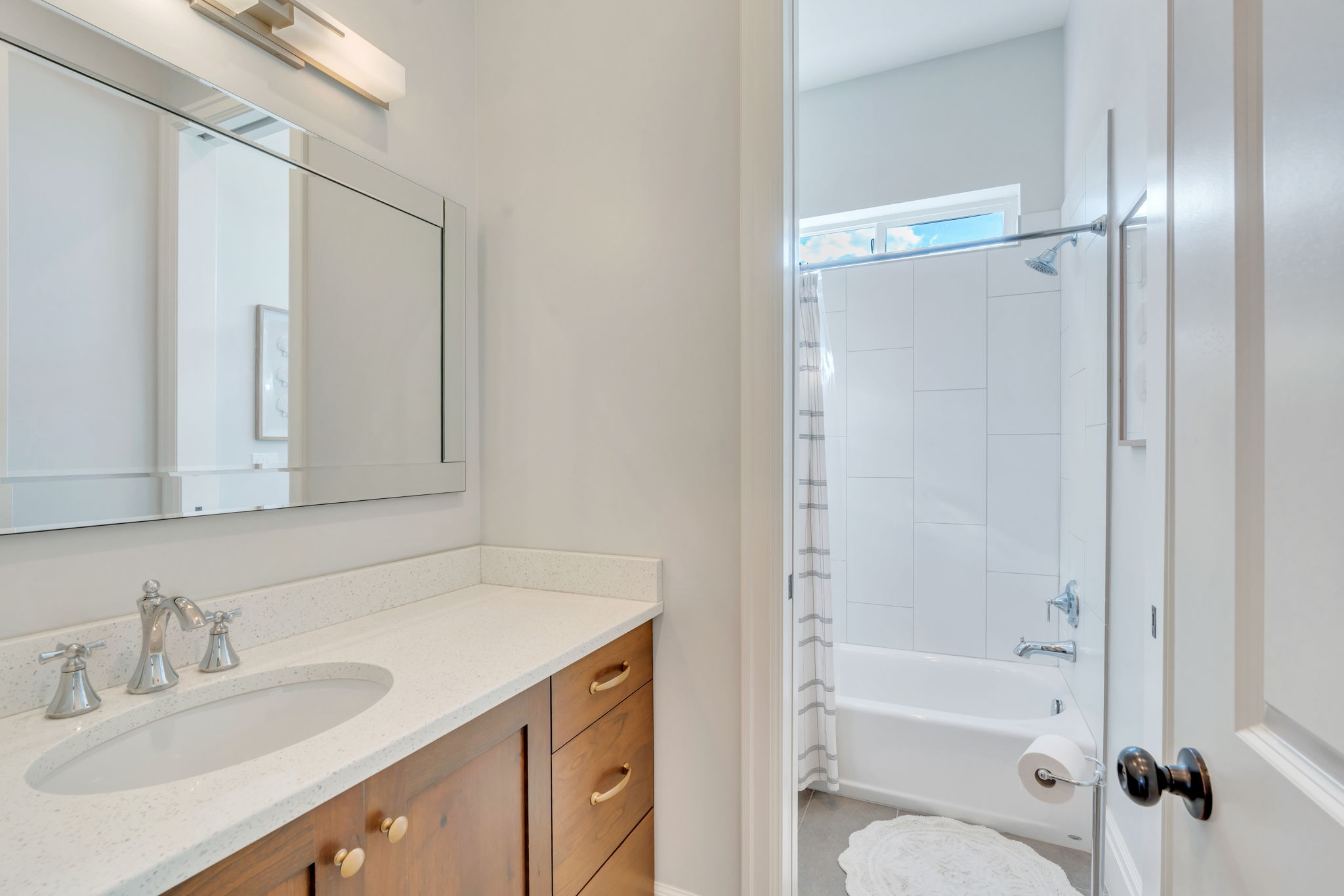 Bathroom vanity featuring a light-toned countertop with integrated sink, chrome-finish faucet, and warm wood-finish cabinetry