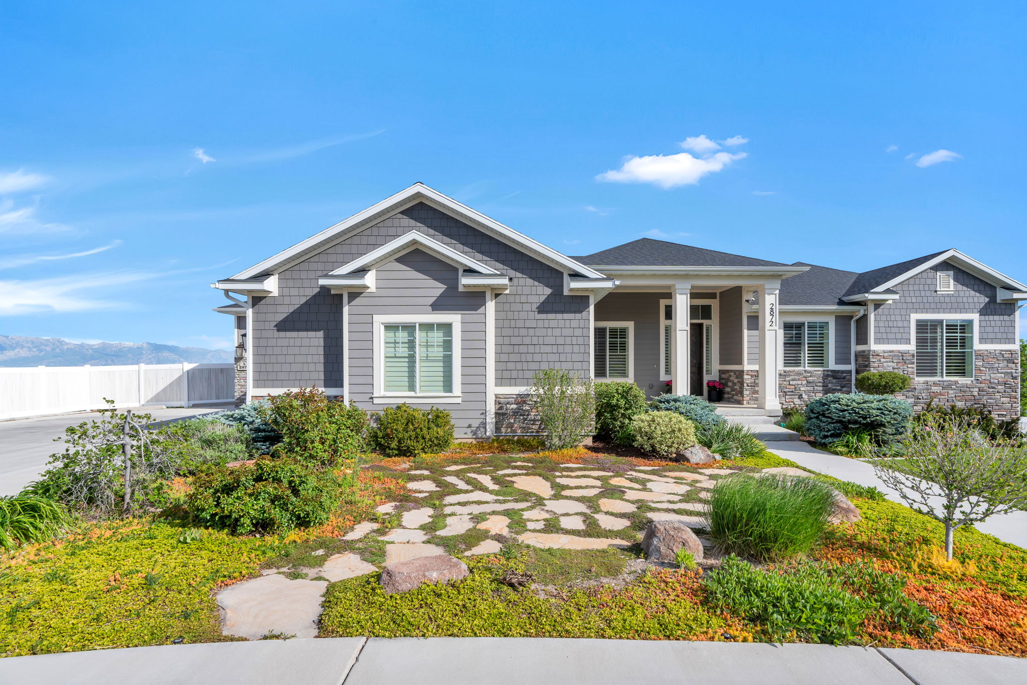 Ranch-style residence featuring a combination of gray siding, shake siding, and stone veneer accents