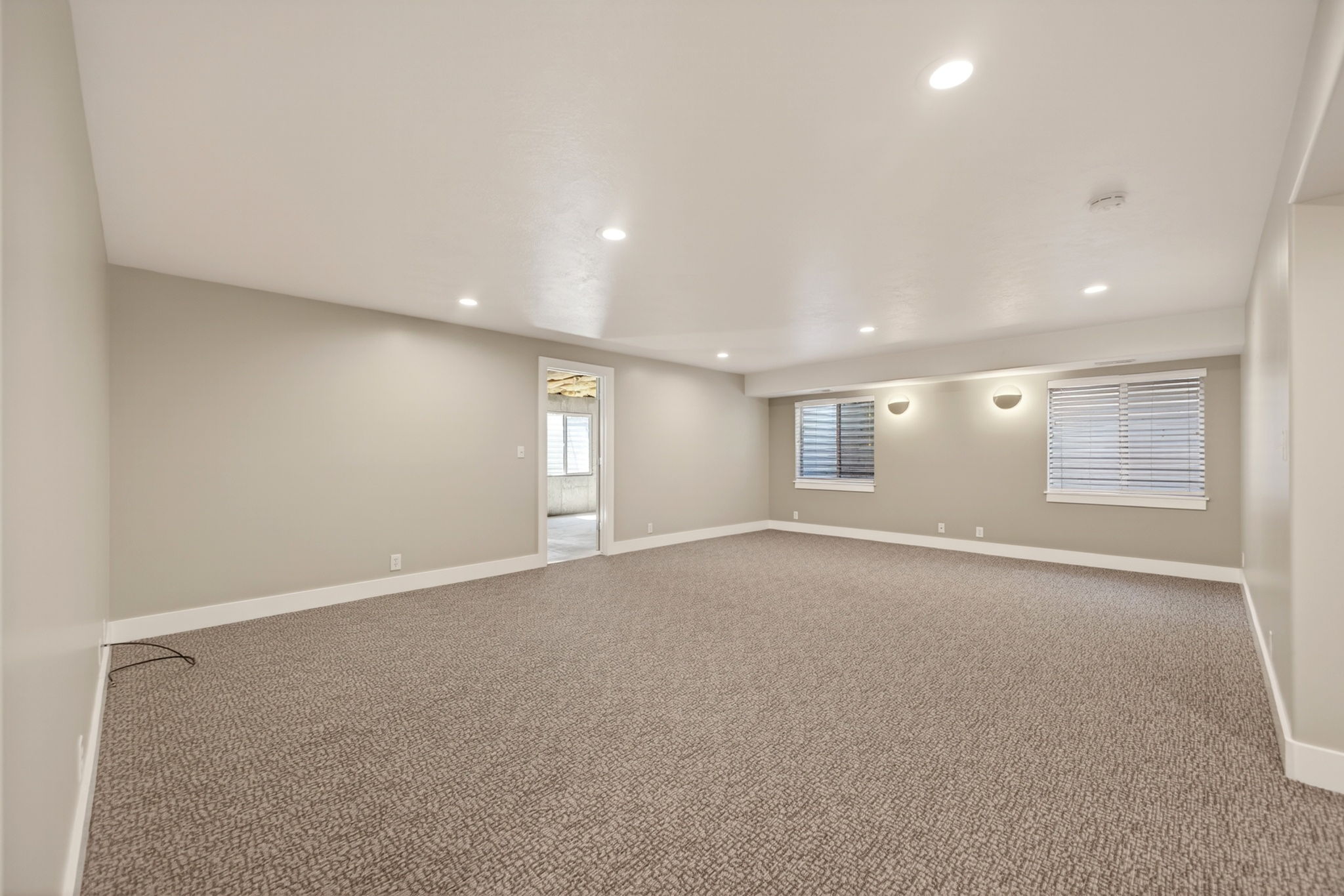 Spacious living room featuring neutral carpeting, light-toned walls, and recessed lighting