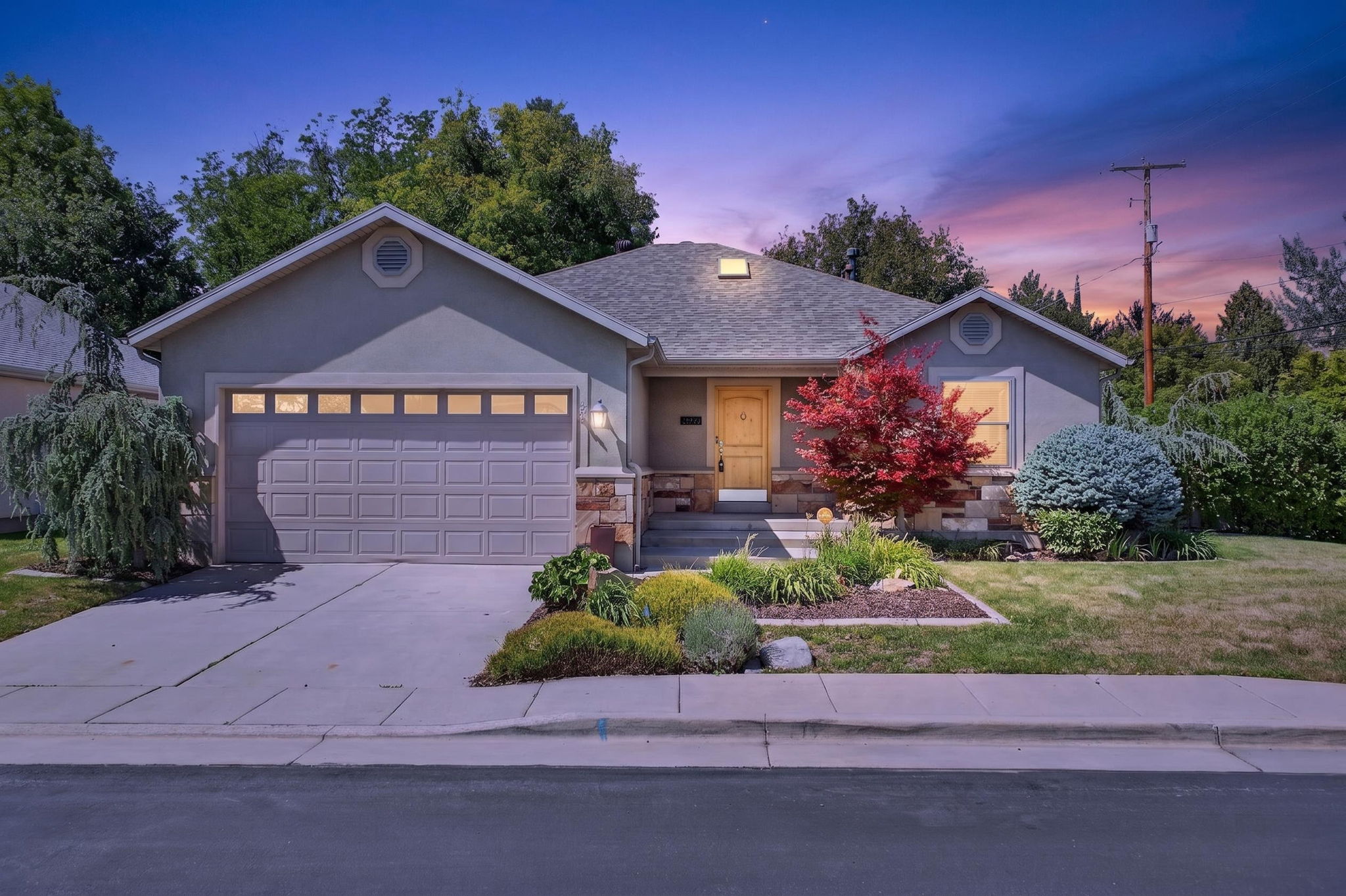 Stucco exterior featuring stone accents, and a gabled roofline