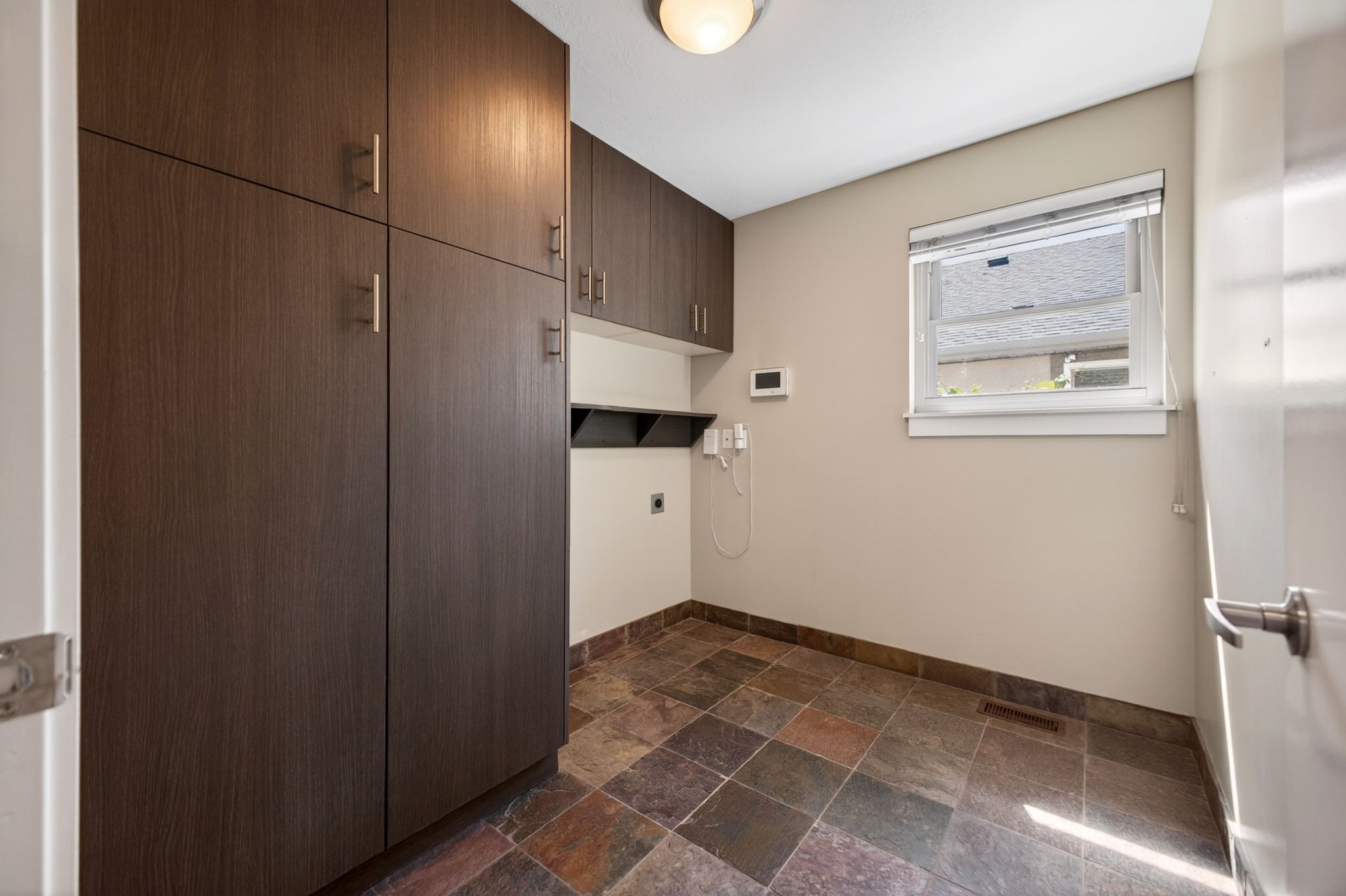 Large laundry room with expansive built-in cabinetry for extensive storage and slate tile floors