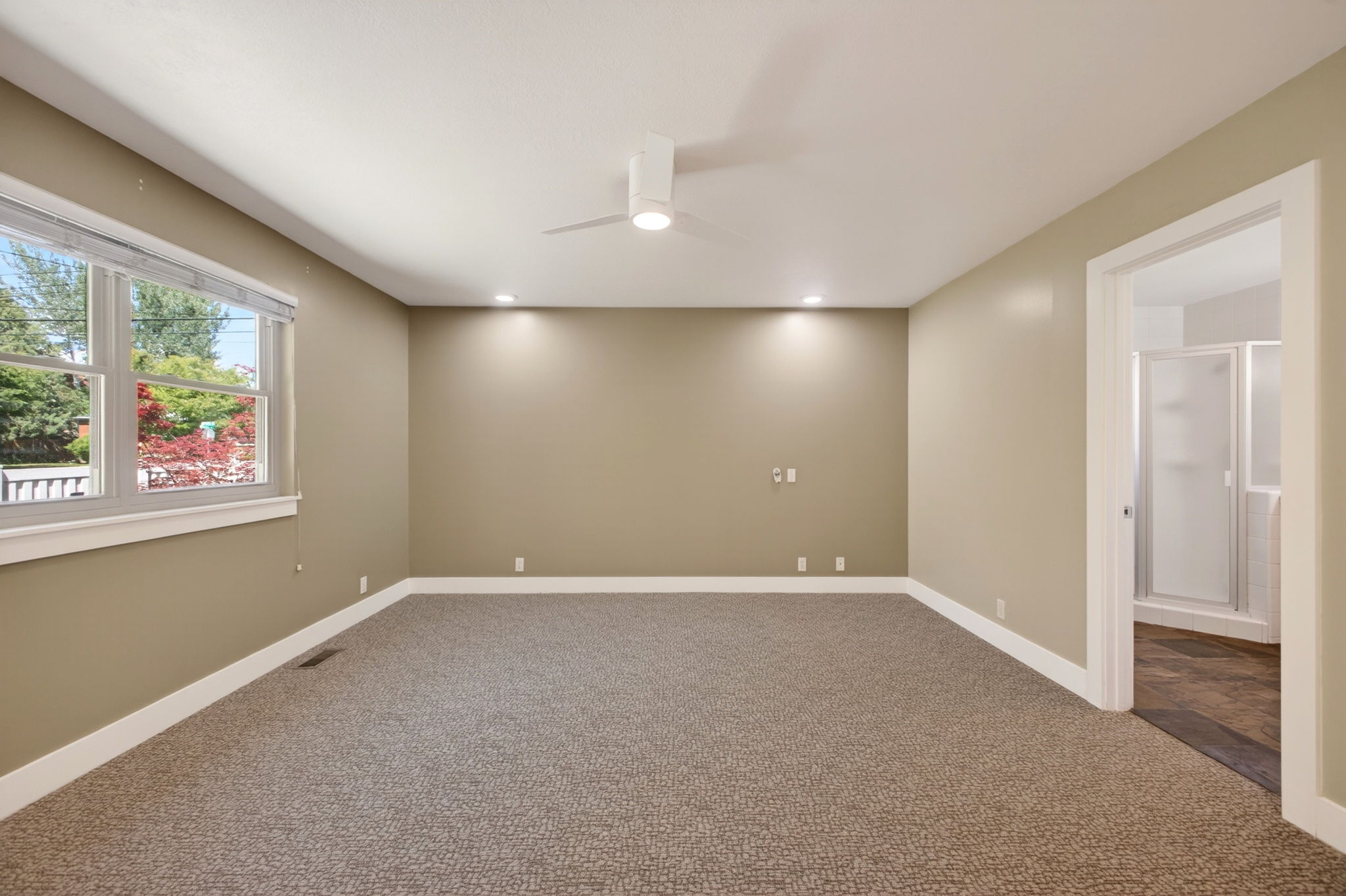 Spacious main bedroom featuring neutral-toned walls, large window, recessed lighting and ceiling fan
