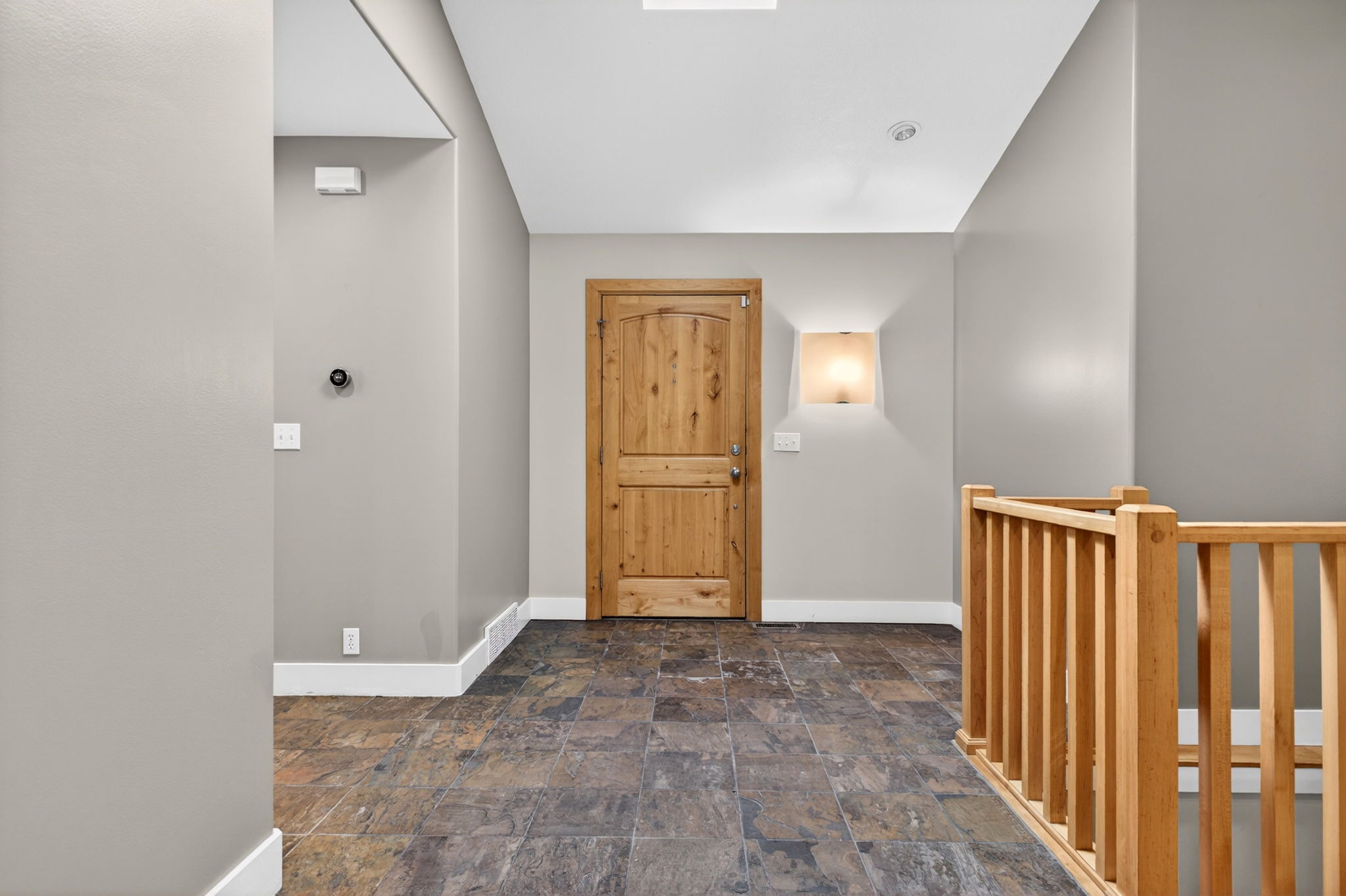 Entryway featuring dark slate tile flooring, light wood door, and skylight