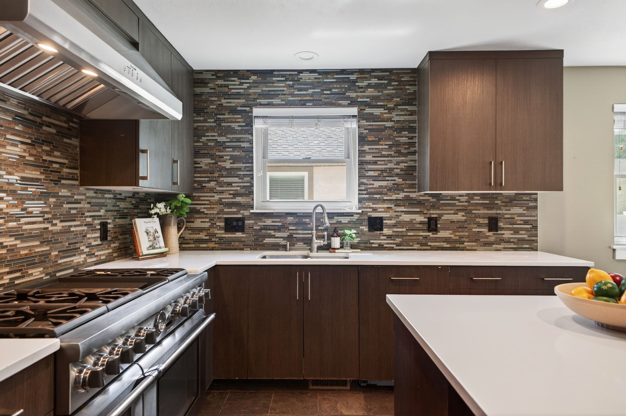 Large kitchen featuring a stainless steel range with matching vent hood, double ovens, white countertops, and a mosaic tile backsplash
