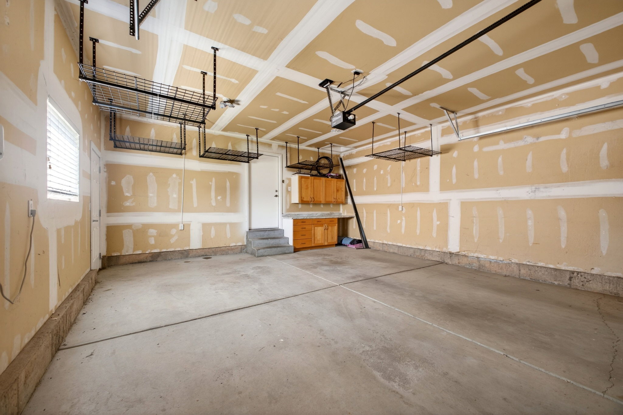 2-car garage featuring a concrete floor, built-in overhead storage racks, a window, and built-in wood cabinetry workspace with countertop