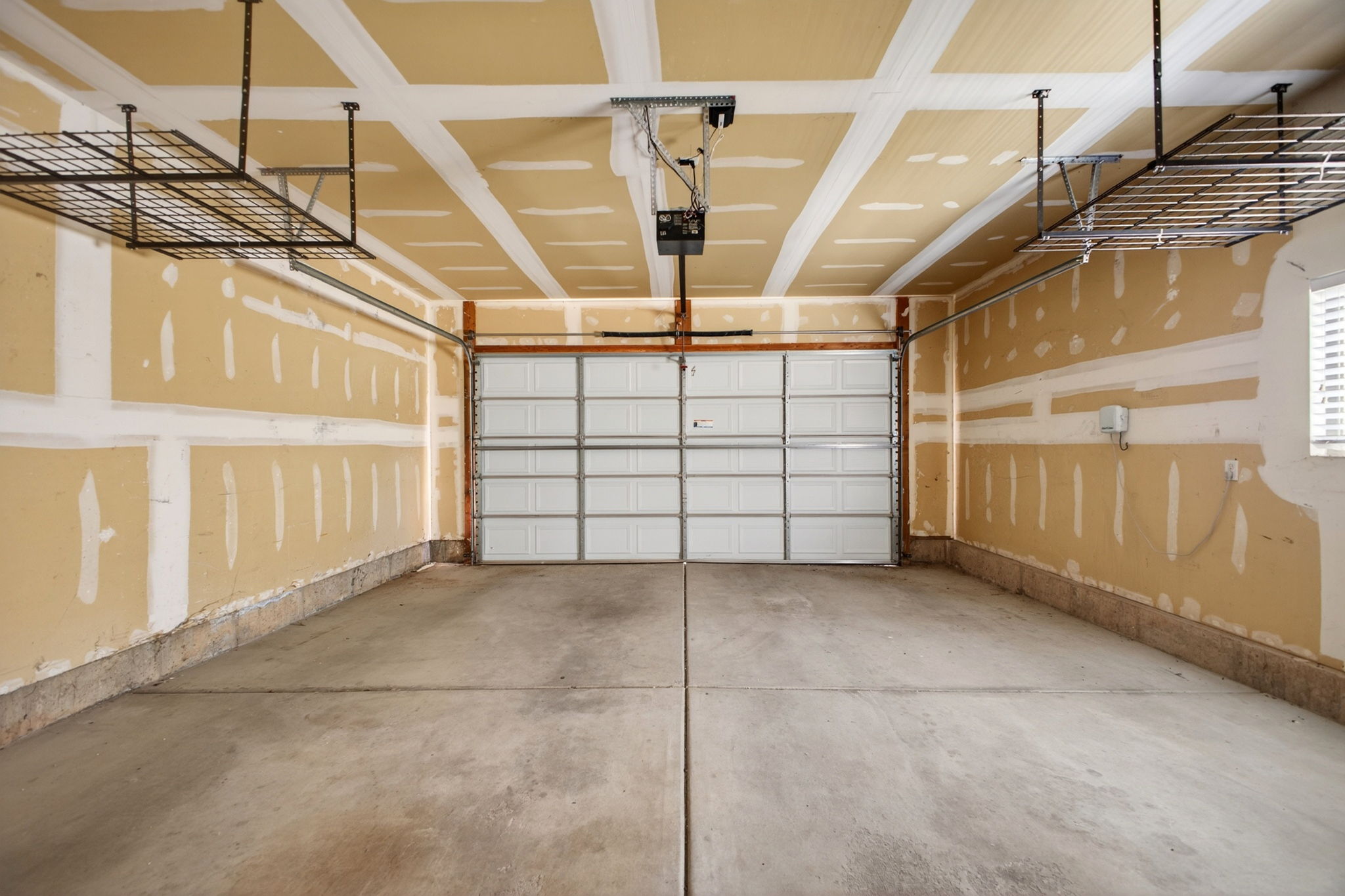 Spacious garage featuring a concrete floor, overhead storage racks, and an automatic garage door opener