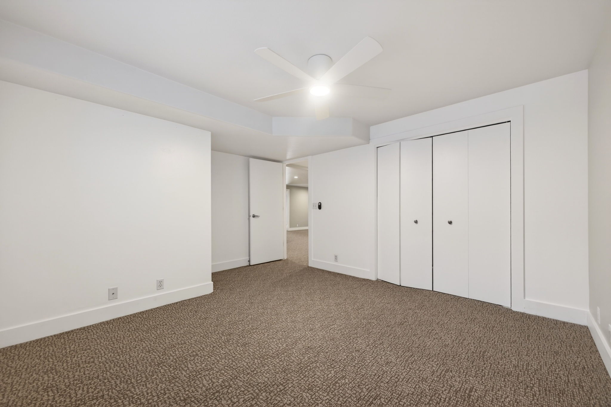 Spacious bedroom featuring bright overhead lighting with a ceiling fan and large closet