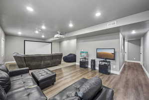 Dedicated entertainment space featuring a large projection screen, recessed lighting, and wood-finish flooring
