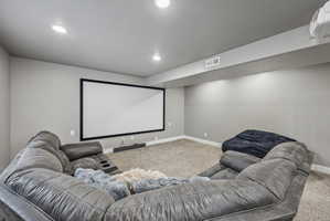 Dedicated media room featuring a large projection screen, recessed ceiling lighting, and wall-mounted projector