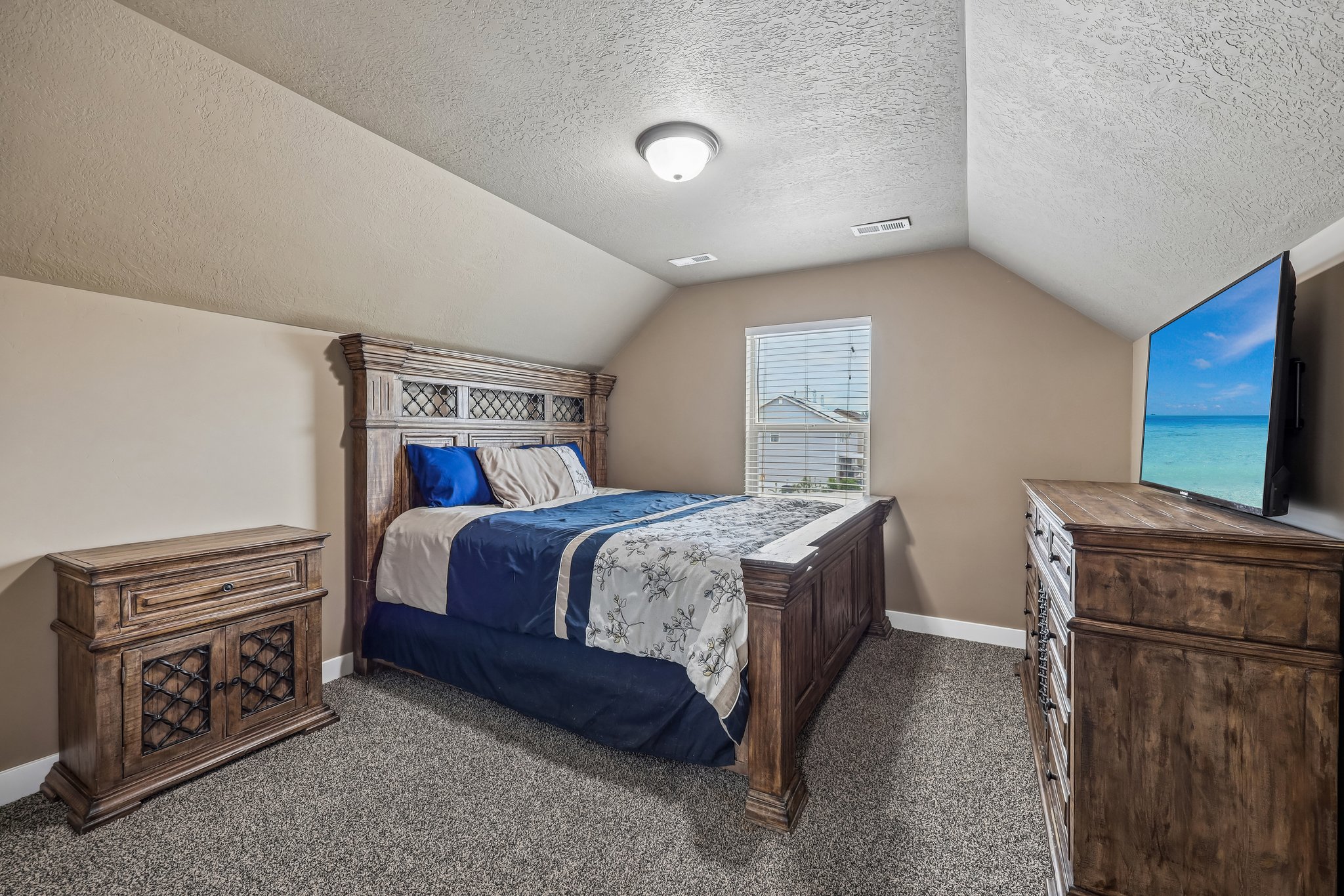 Carpeted bedroom featuring an angled ceiling, a single window with blinds, and a flush-mount ceiling light