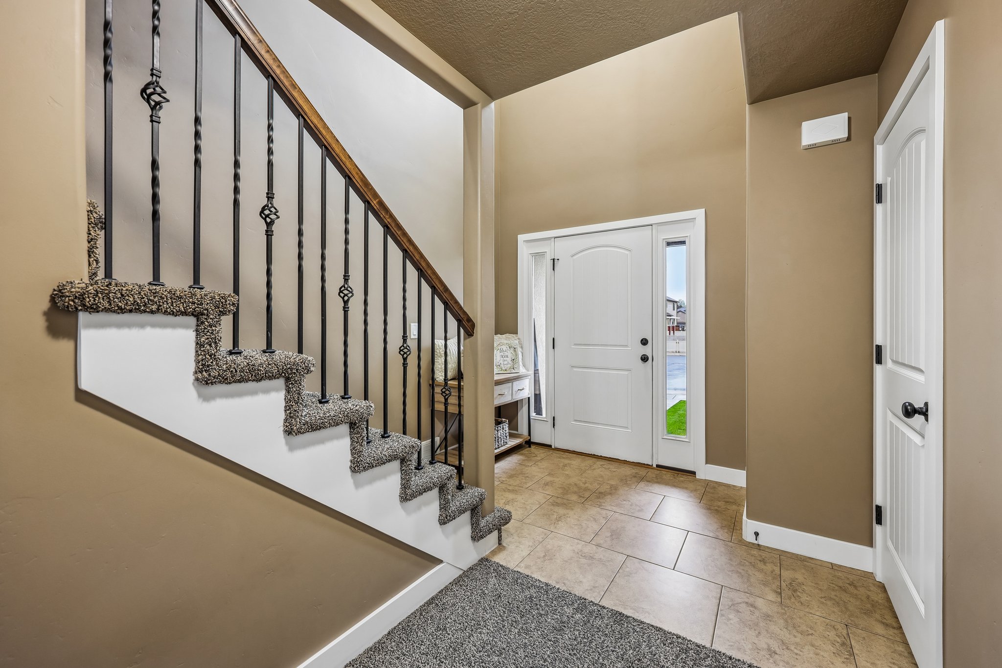 Entryway featuring a carpeted staircase with wrought iron balusters and a wood handrail