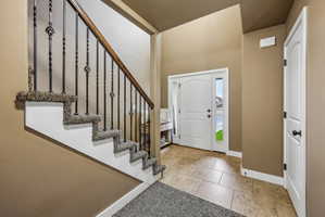 Entryway featuring a carpeted staircase with wrought iron balusters and a wood handrail