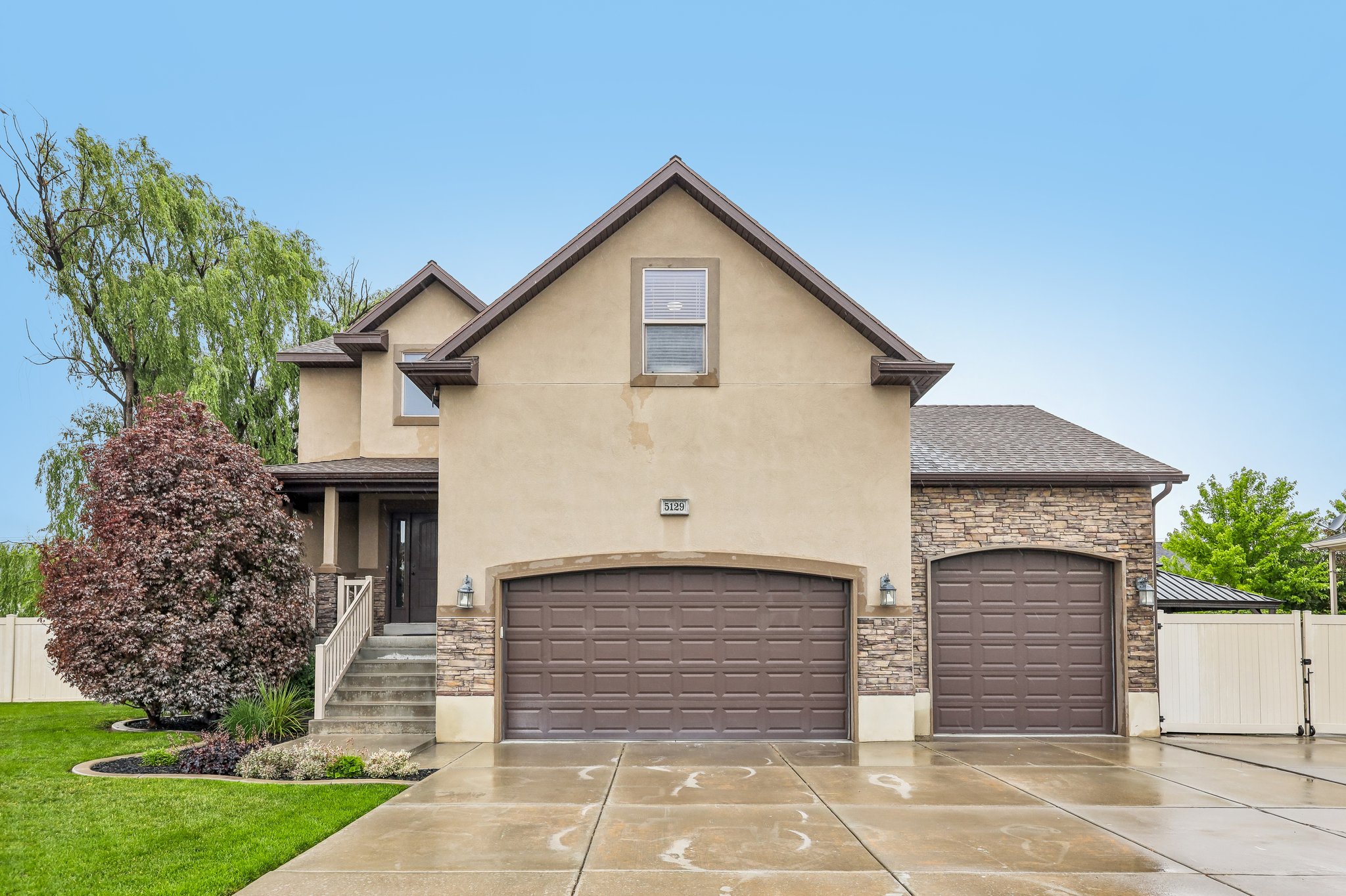 Stucco and stone exterior featuring a two-car garage and an additional single-car garage