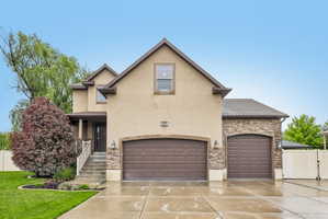 Stucco and stone exterior featuring a two-car garage and an additional single-car garage
