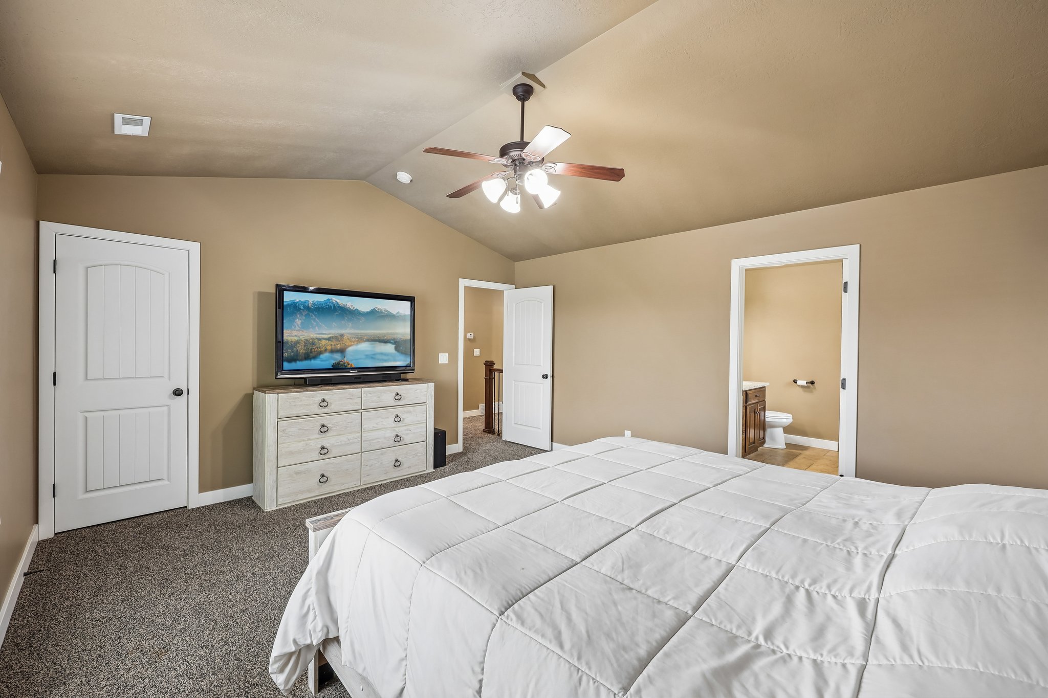Carpeted room featuring a vaulted ceiling and a ceiling fan with light fixture
