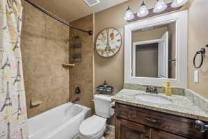 Bathroom featuring a tub/shower combination with tile surround, a dark wood-finish vanity with granite countertop, an undermount sink, and a framed mirror with overhead lighting