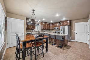 Open-concept kitchen and dining area featuring rich wood cabinetry, stone backsplash, and granite countertops