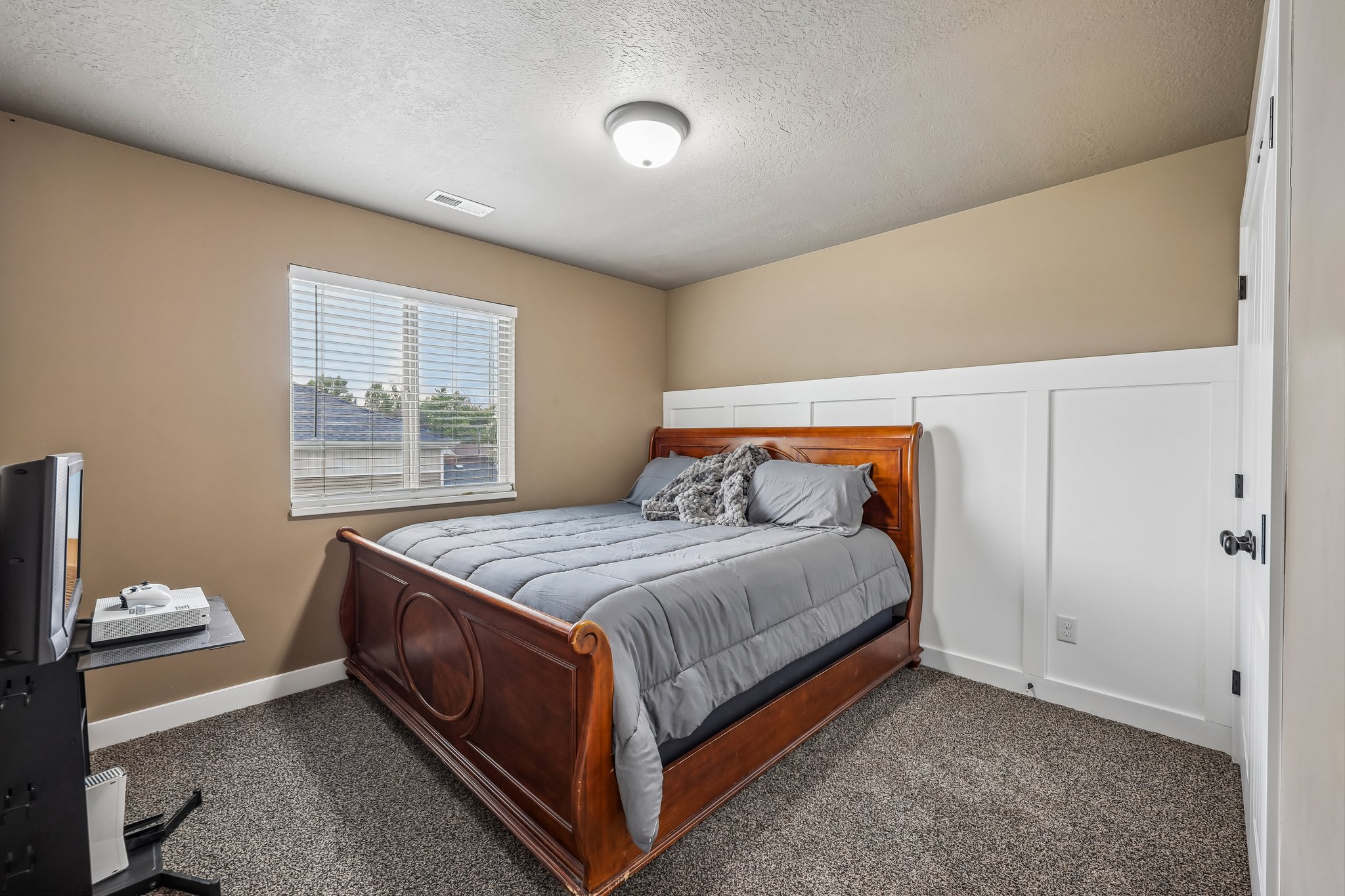Carpeted room featuring a window with blinds, board and batten wall paneling, and an overhead light fixture