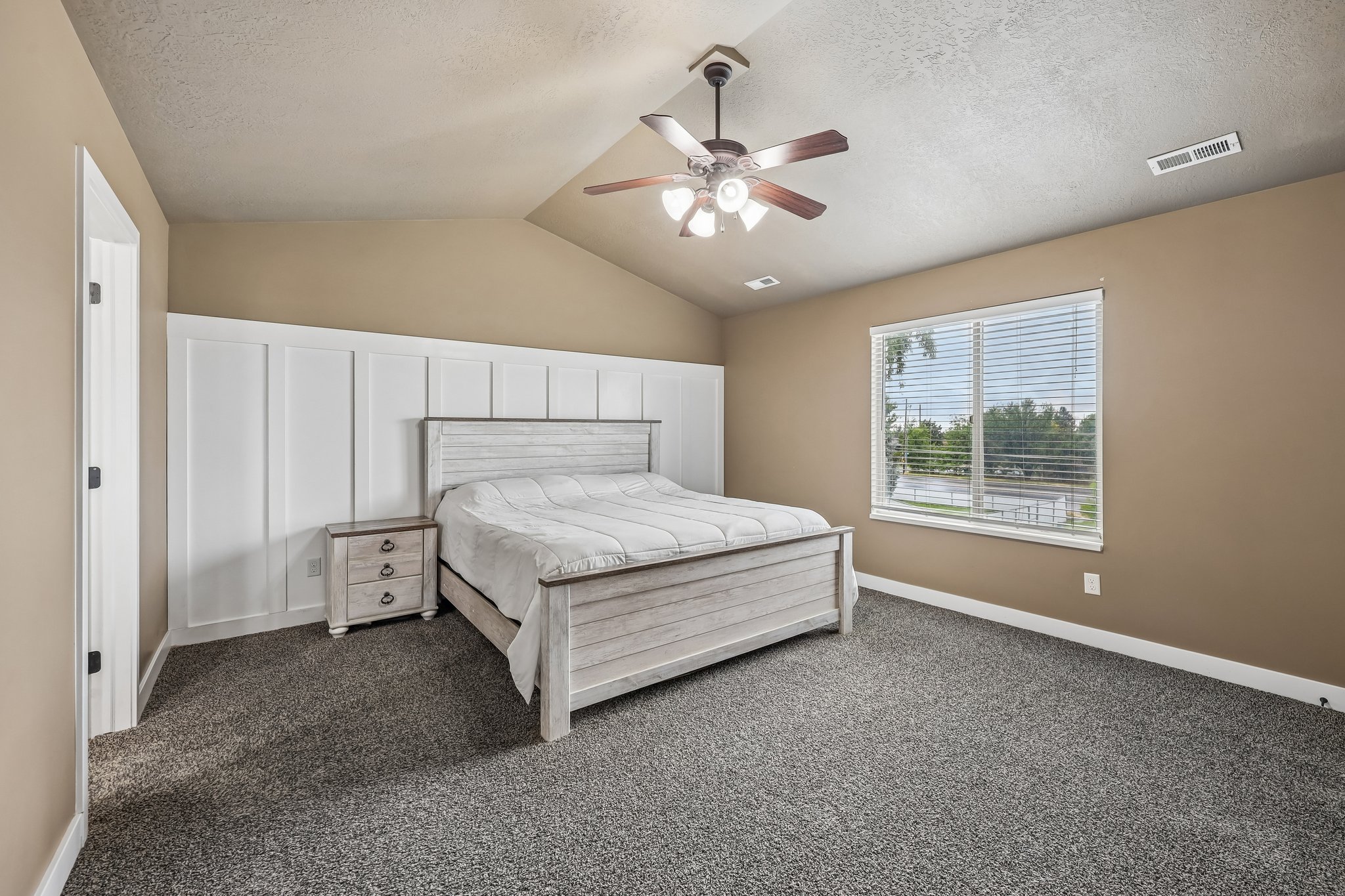 Room featuring vaulted ceilings with a ceiling fan, plush carpet flooring, and a large window with horizontal blinds
