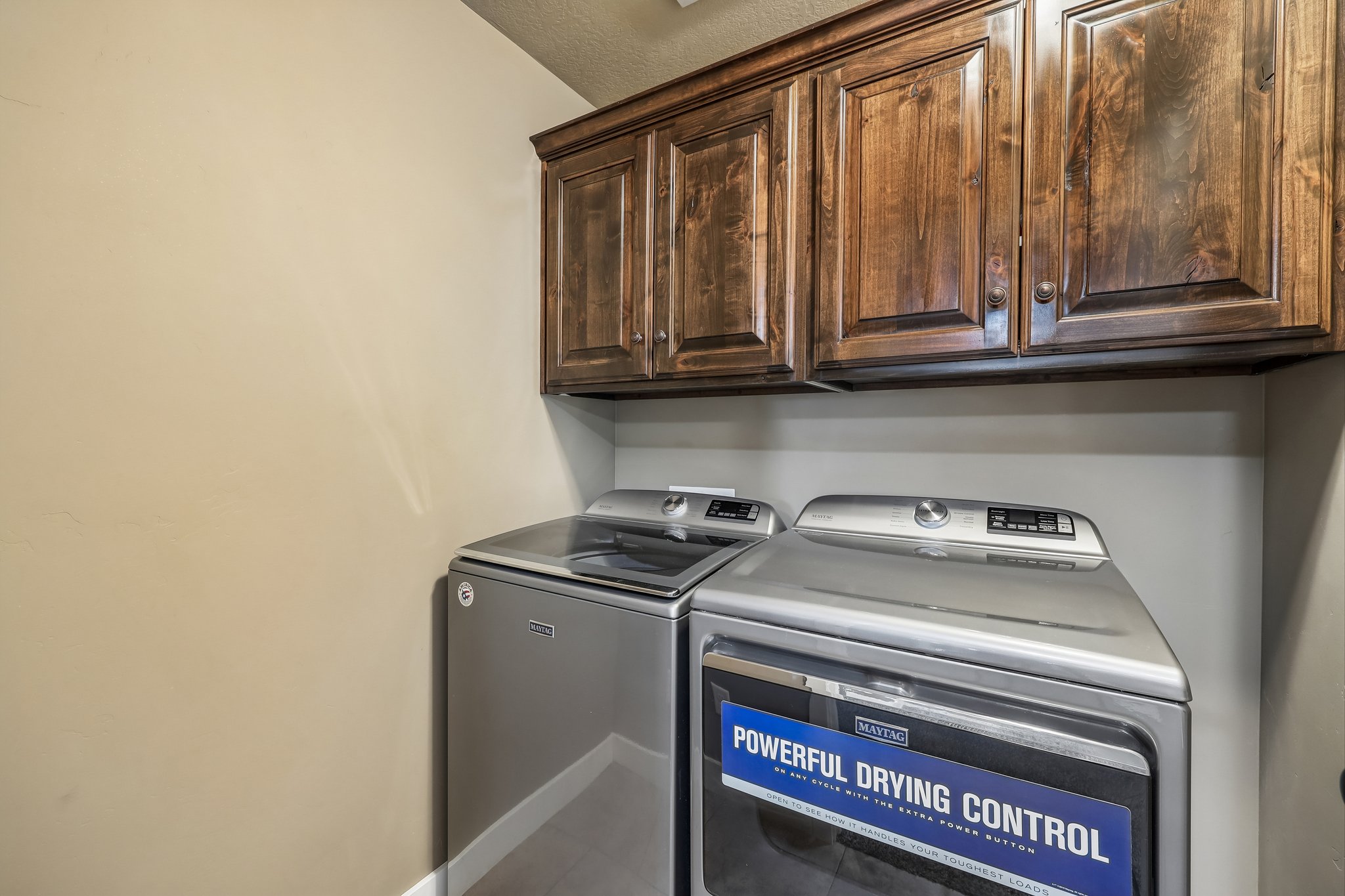 Laundry area featuring wood-finish cabinetry and neutral wall tones