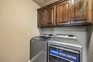 Laundry area featuring wood-finish cabinetry and neutral wall tones