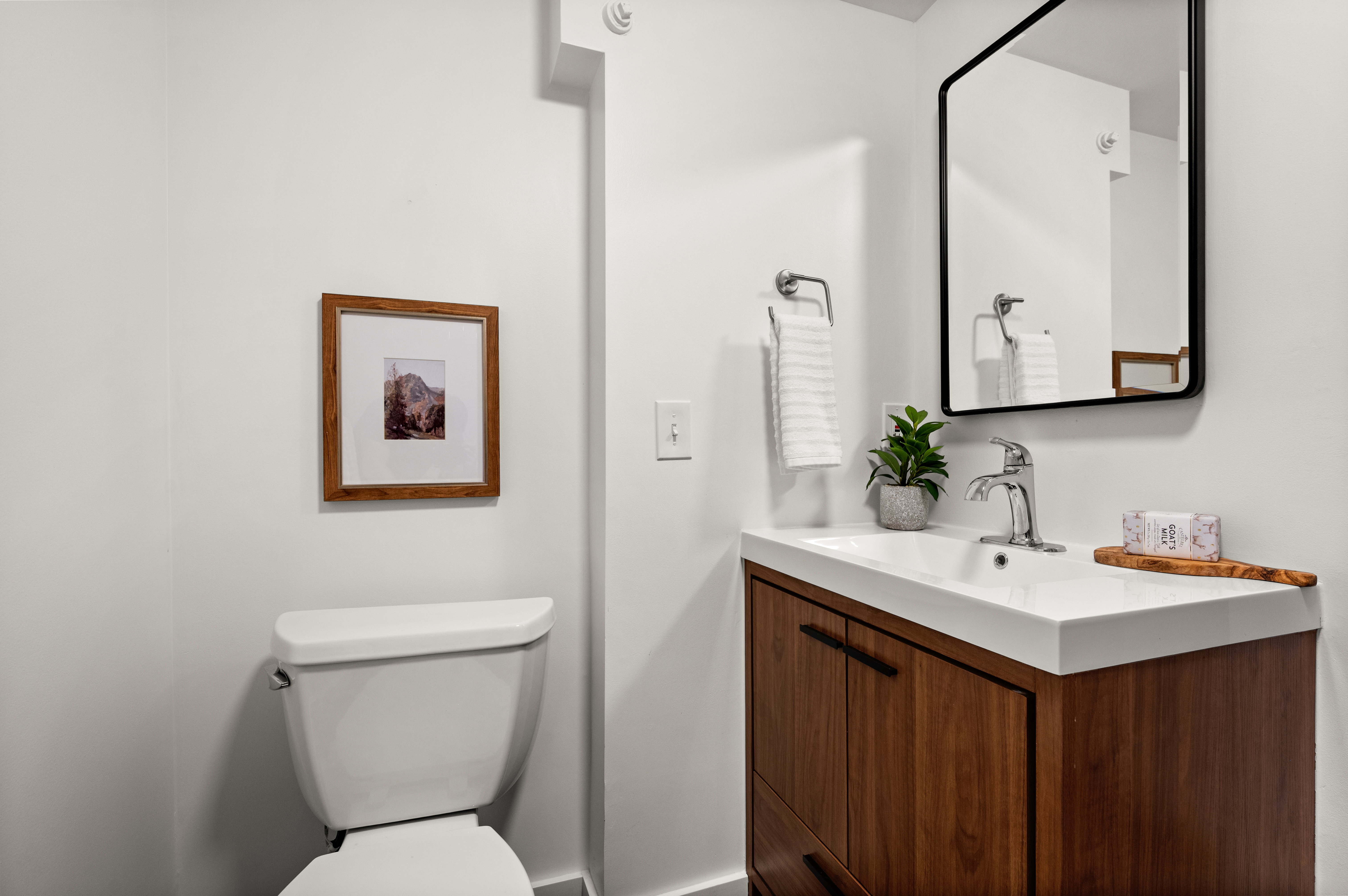 Modern vanity featuring a wood-finish cabinet with black hardware, a rectangular integrated sink, and a chrome faucet