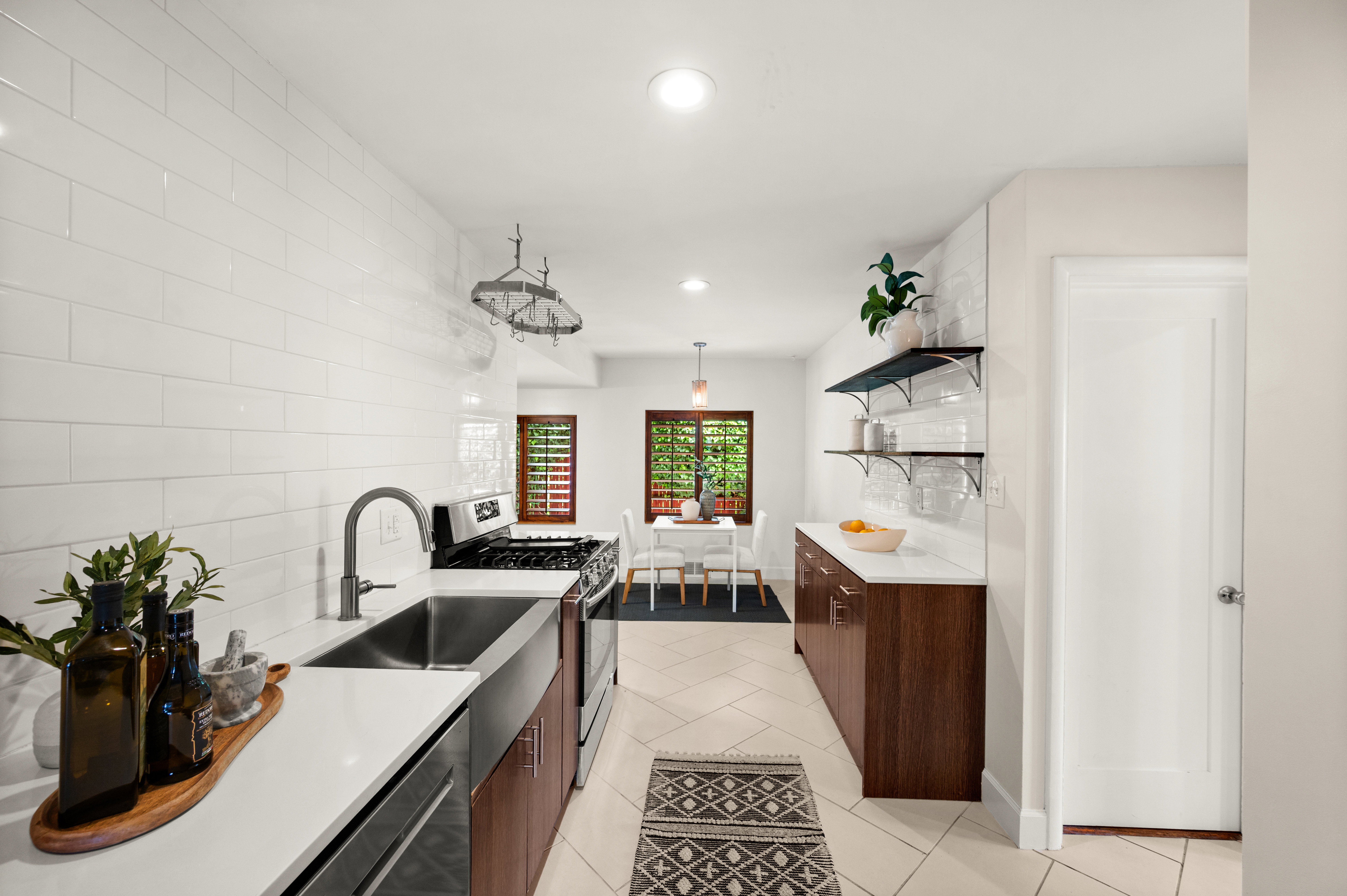 Contemporary kitchen featuring white subway tile backsplash, white countertops, stainless steel appliances, and wood-finish cabinetry
