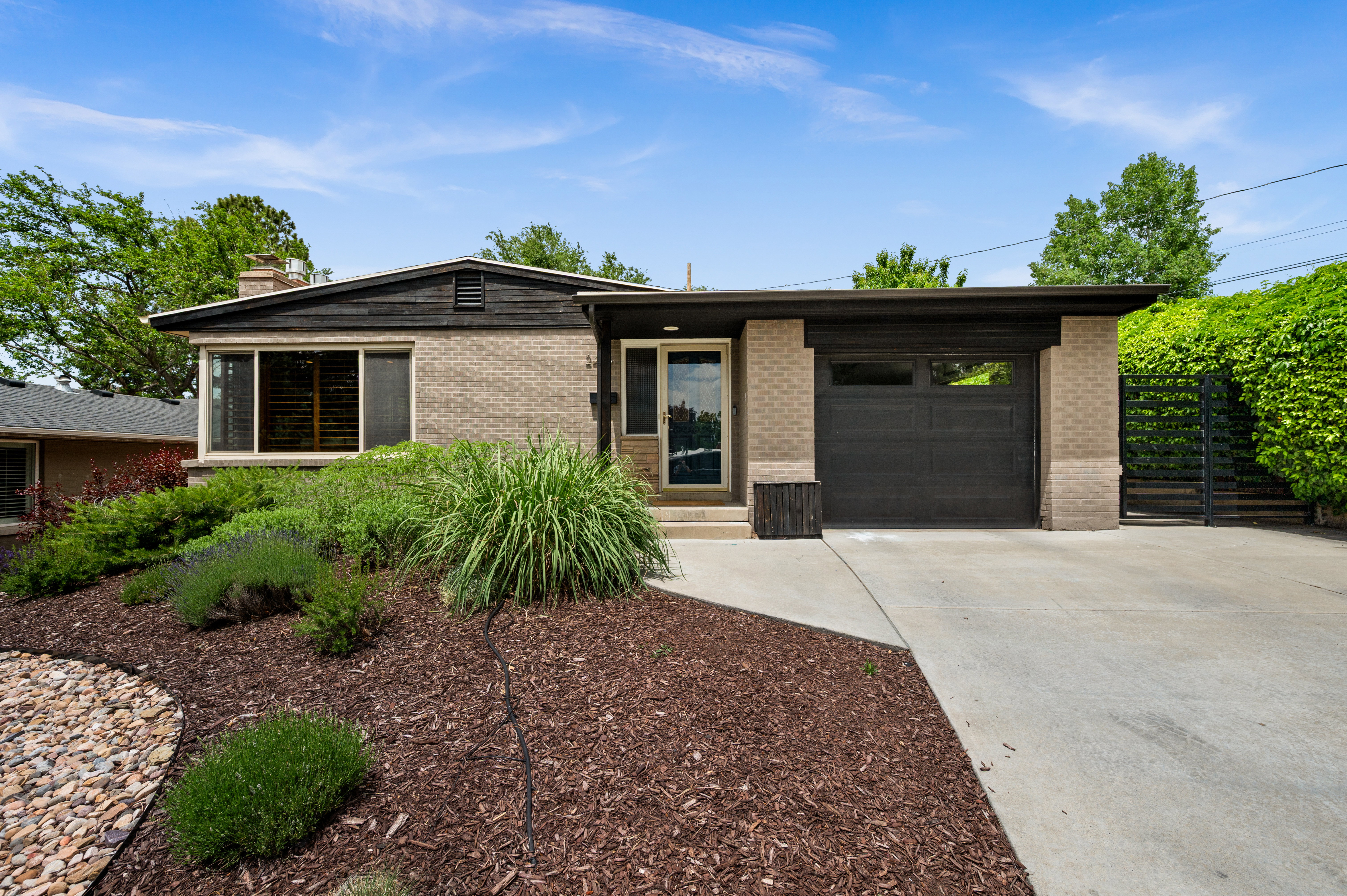 Mid-century modern exterior featuring brick and dark wood siding