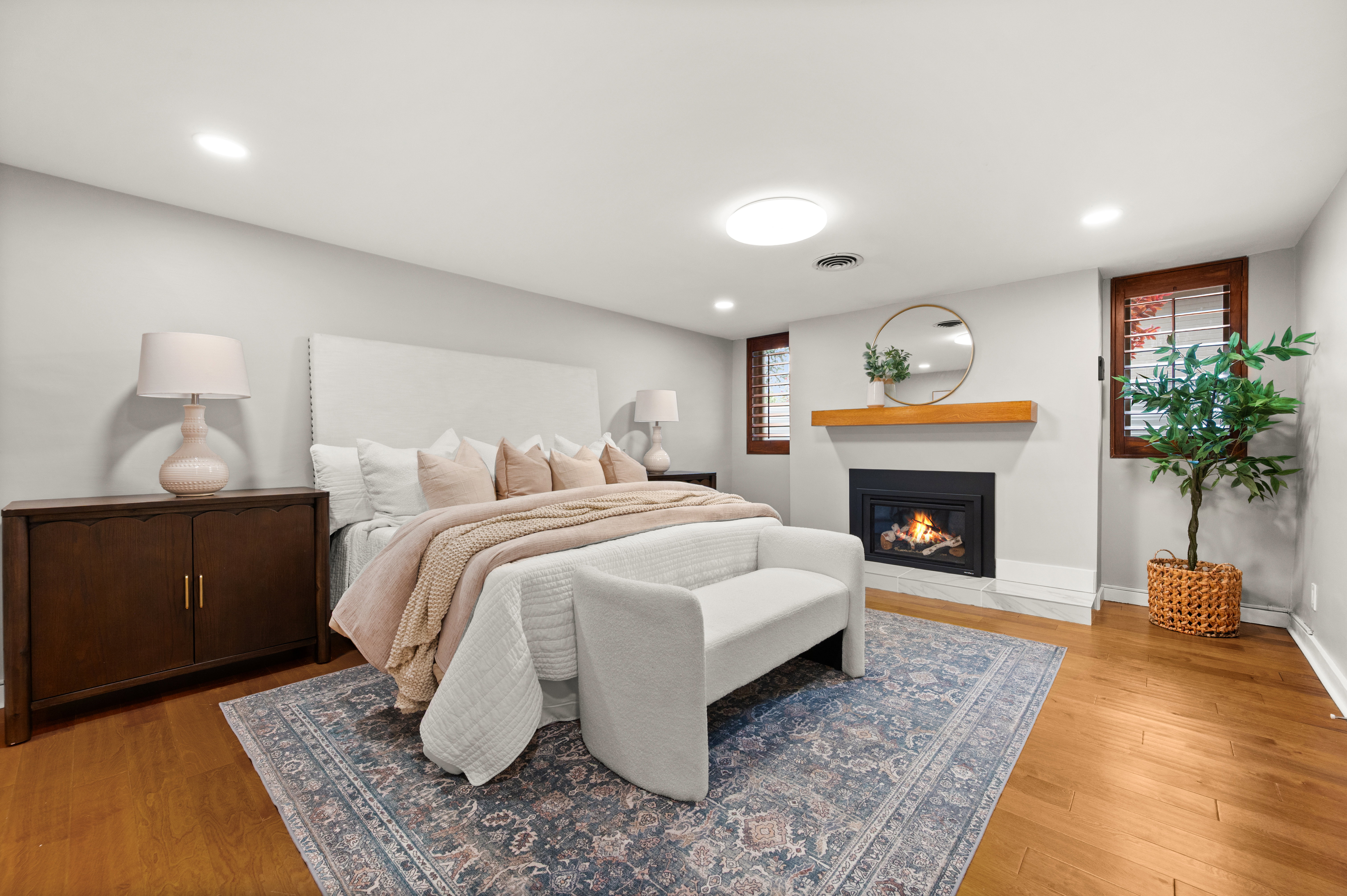 Hardwood flooring throughout featuring a built-in fireplace with a white hearth and wood mantel